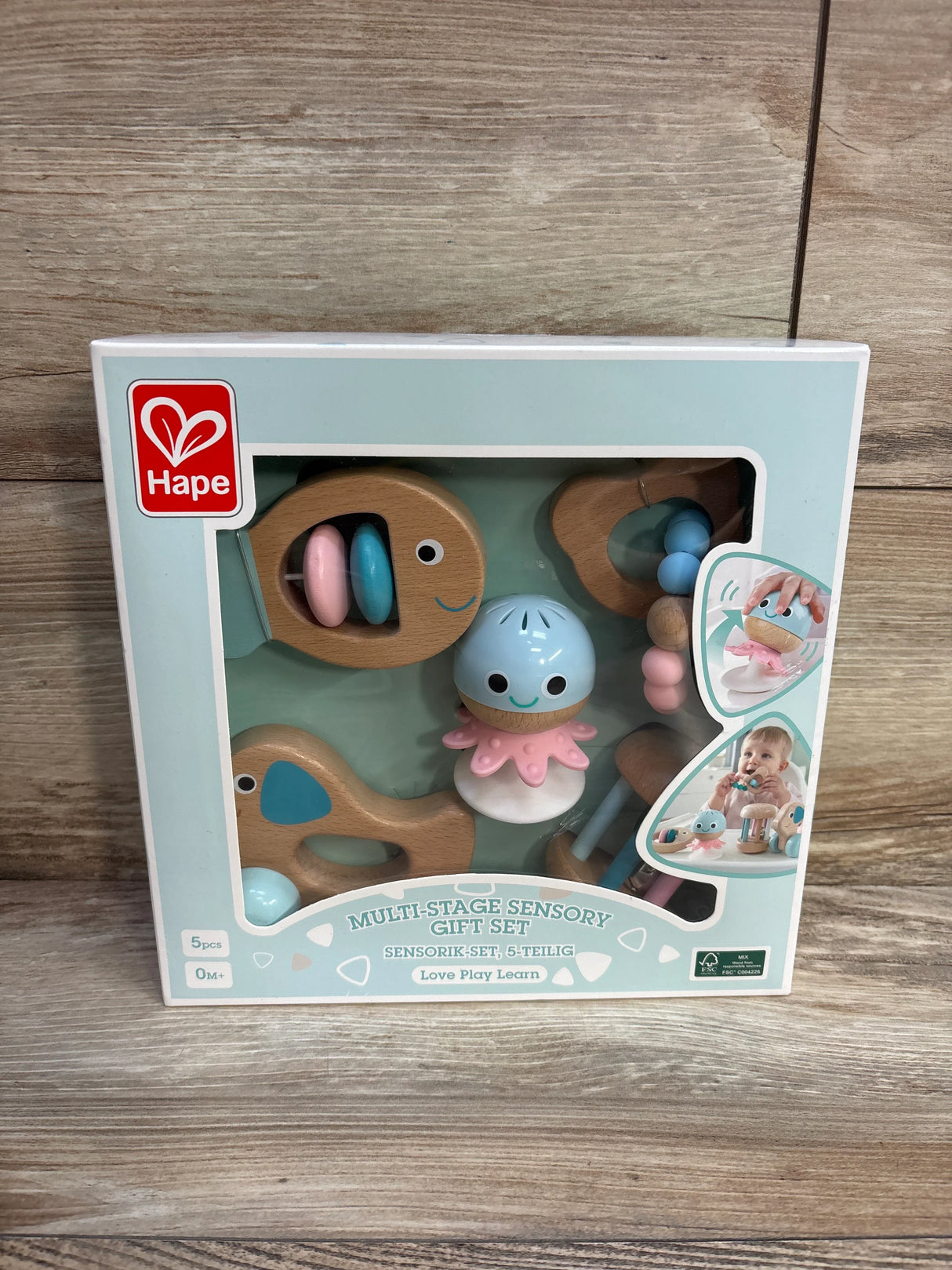 Hape multi-stage sensory gift set for babies in pastel colors, displayed in box on wood floor