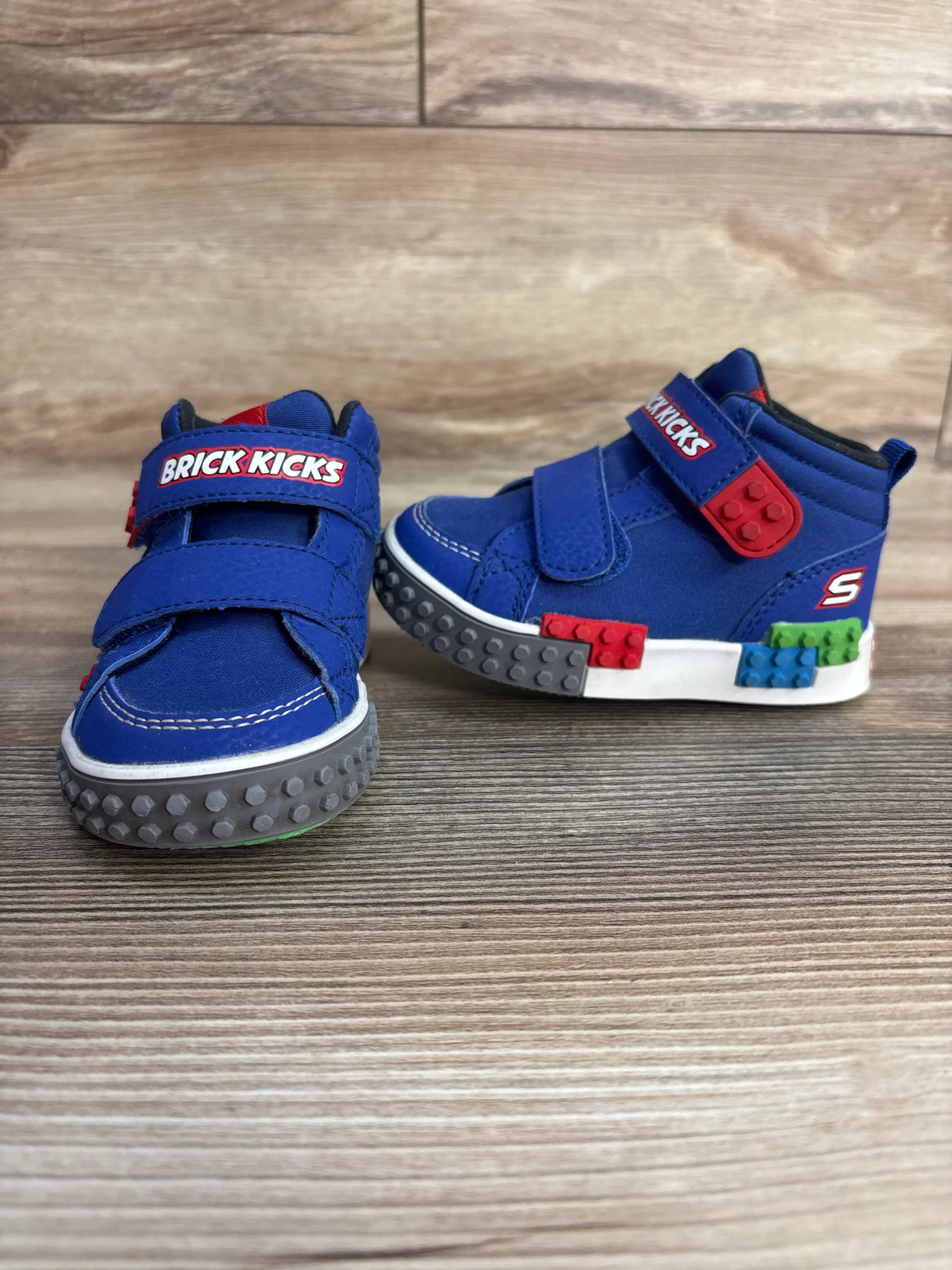 Blue Brick Kicks toddler sneakers with LEGO-style details, velcro straps, wood floor.