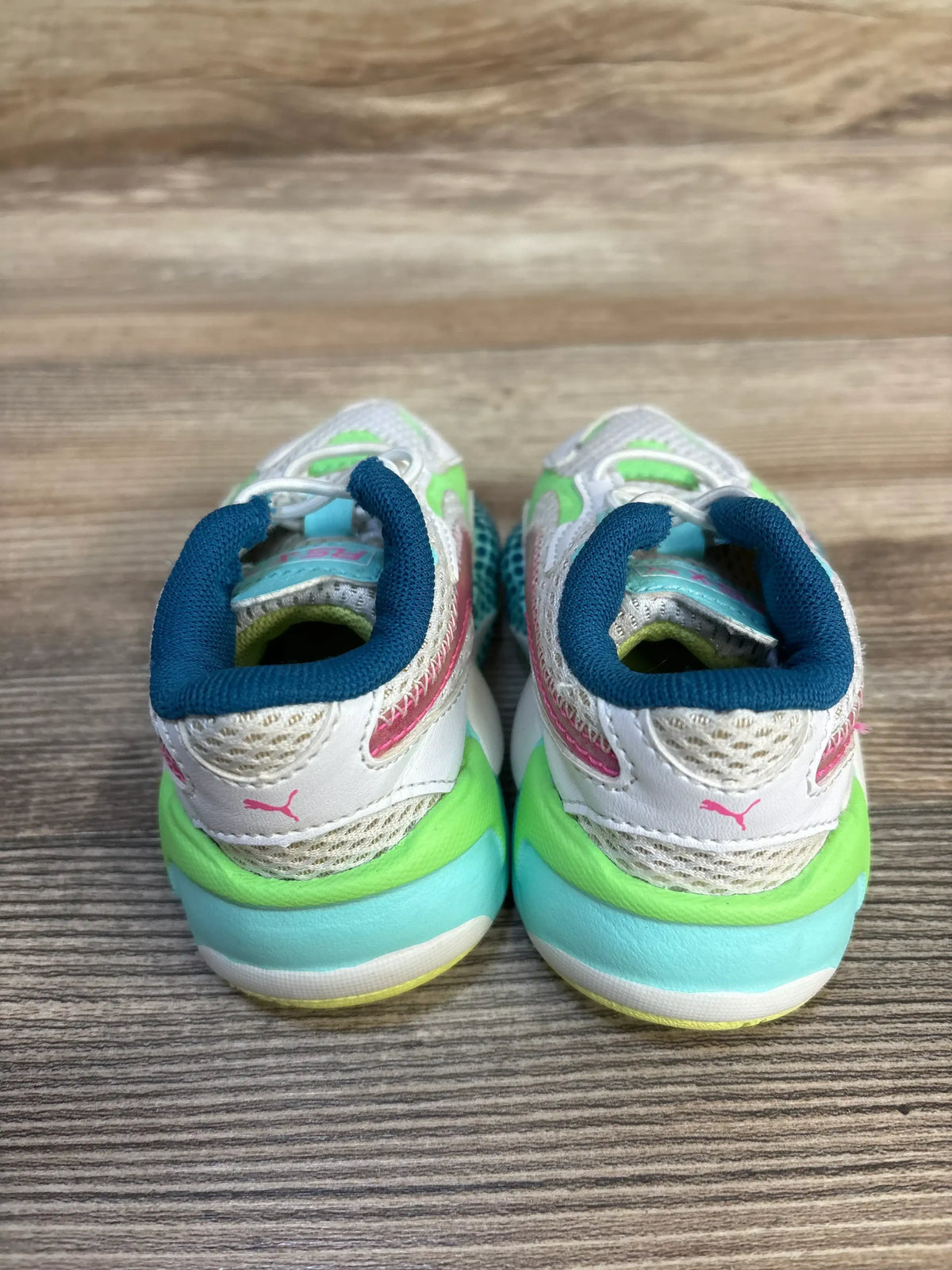 Rear view of Puma RS-X3 WR toddler sneakers showing teal padded collar, pink Puma heel logo, and green-aqua sole on wooden floor