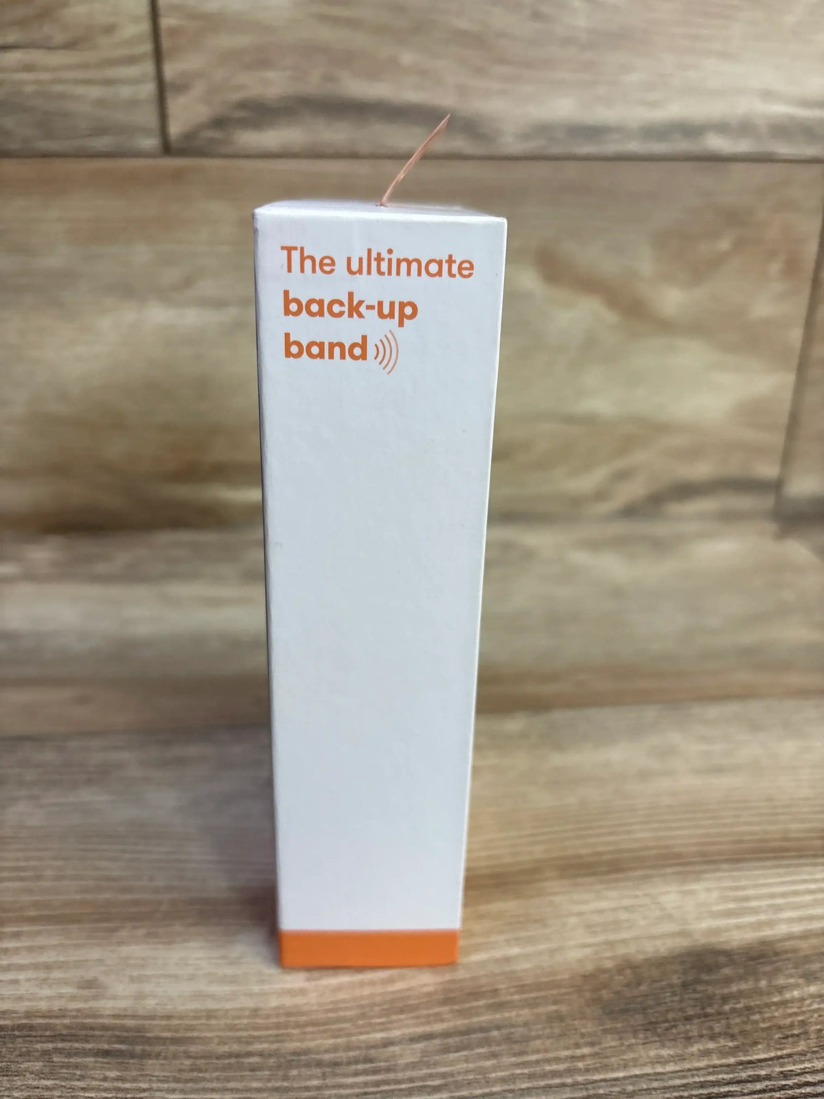 Side view of Frida Mom Anti-Nausea Bands 2-count box showcasing orange accent and headline The ultimate back-up band on wood background