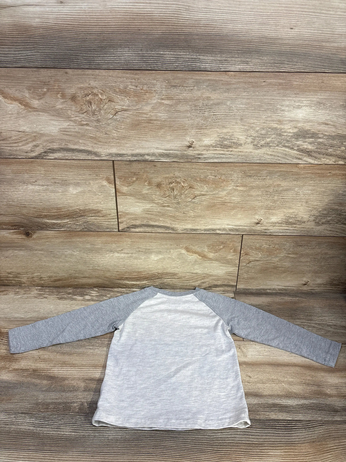 Front view of Lucky Brand 2T grey long sleeve shirt showcasing raglan sleeves on a wood floor
