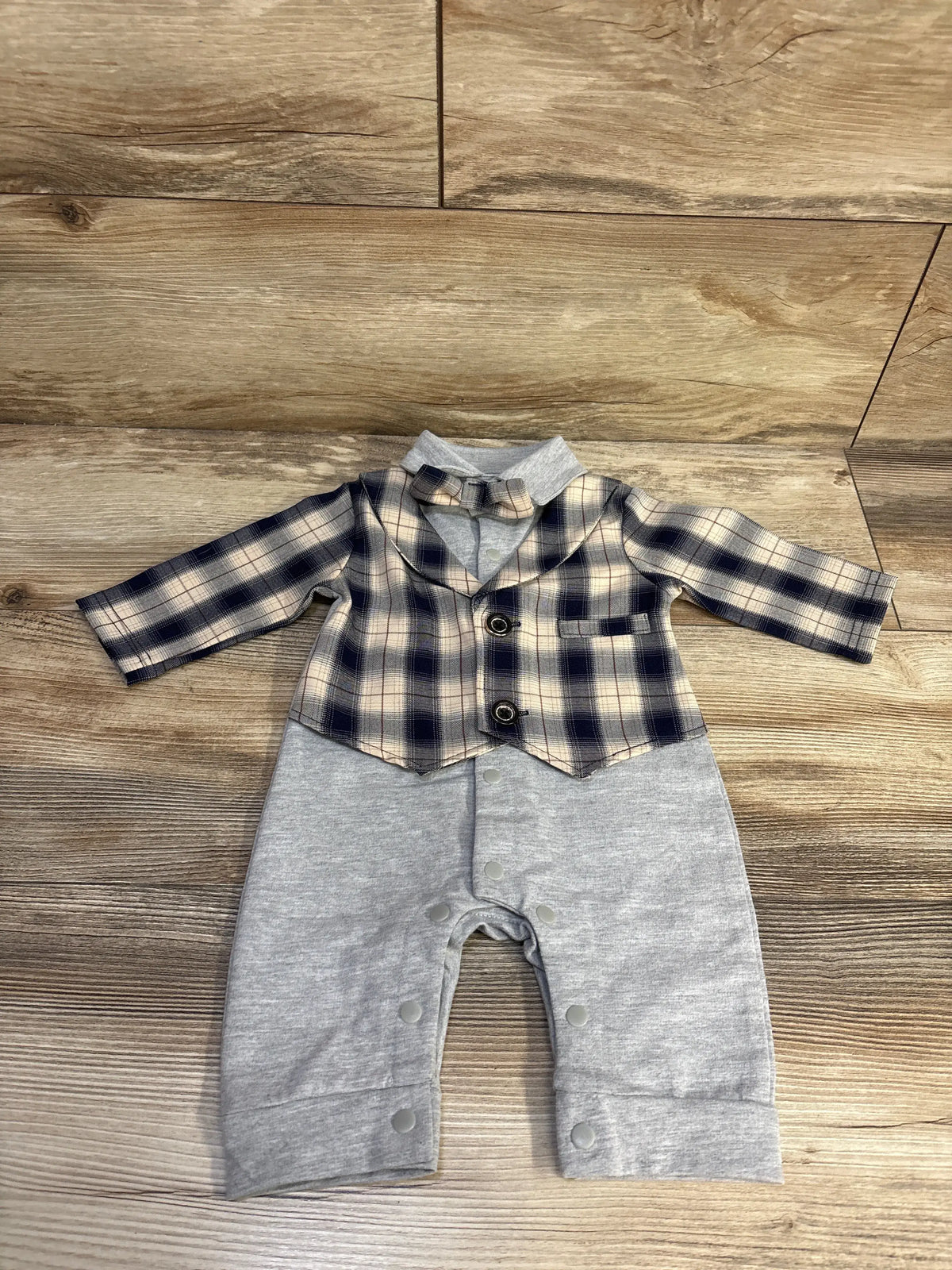 Front view of HOSUKKO grey vest romper showcasing plaid vest, removable bowtie, and snap closures on wood background