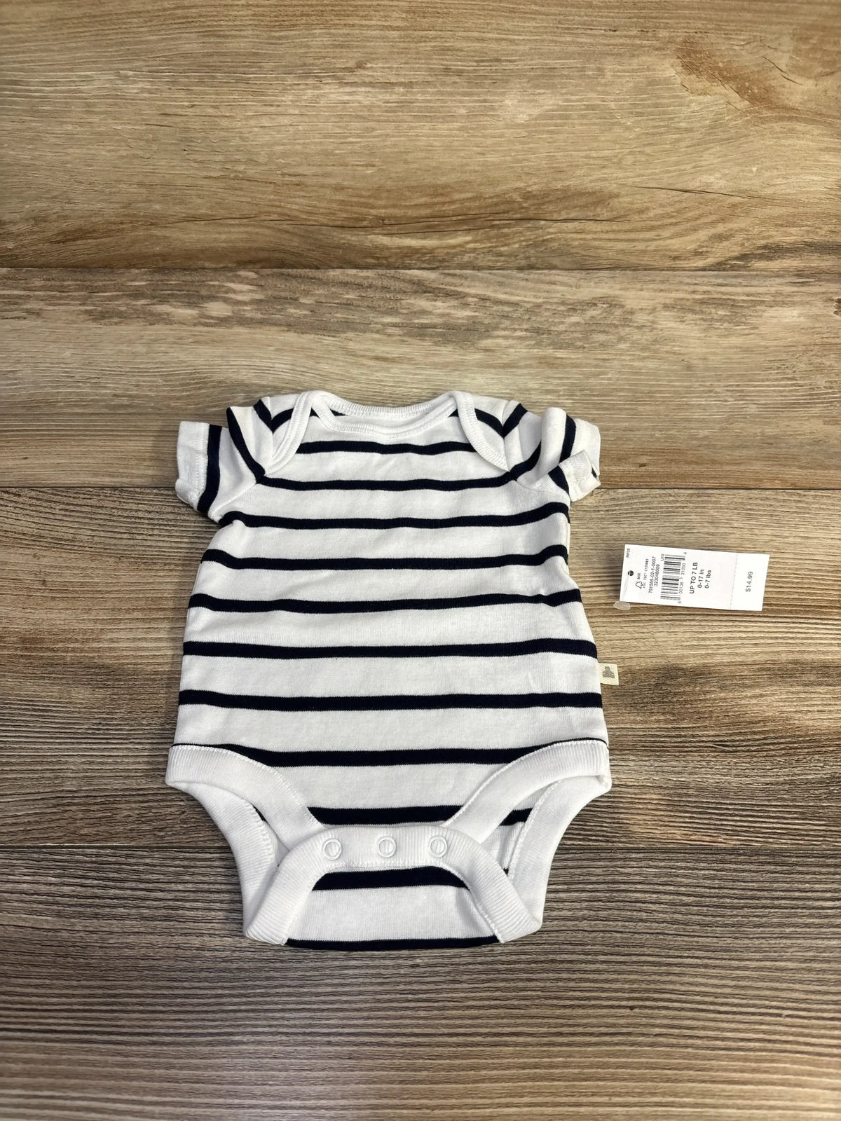 Top down view of newborn white Baby Gap striped bodysuit showing navy stripes, envelope shoulders and three snap crotch on wood background