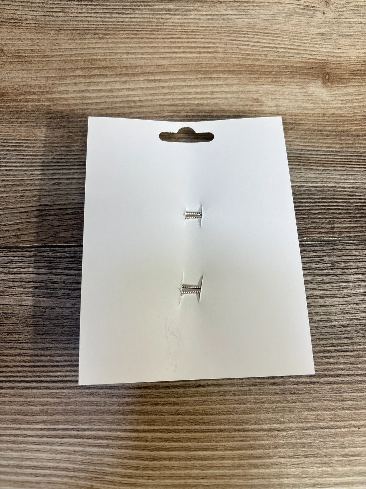 Silver baby safety pins on white card, wooden background