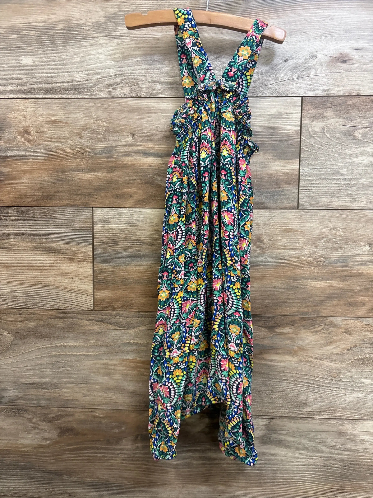 Front view Old Navy tank dress 5T with multicolor floral print and ruffled straps on wooden hanger against wood background