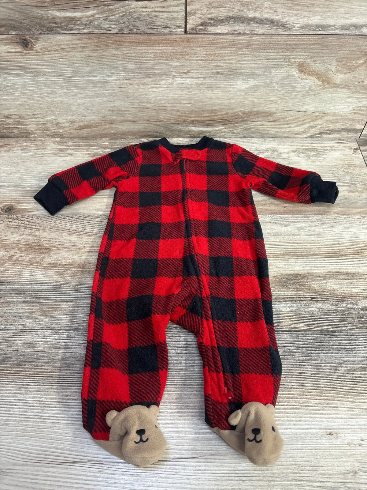 Red and black plaid baby sleeper with bear feet on wood background