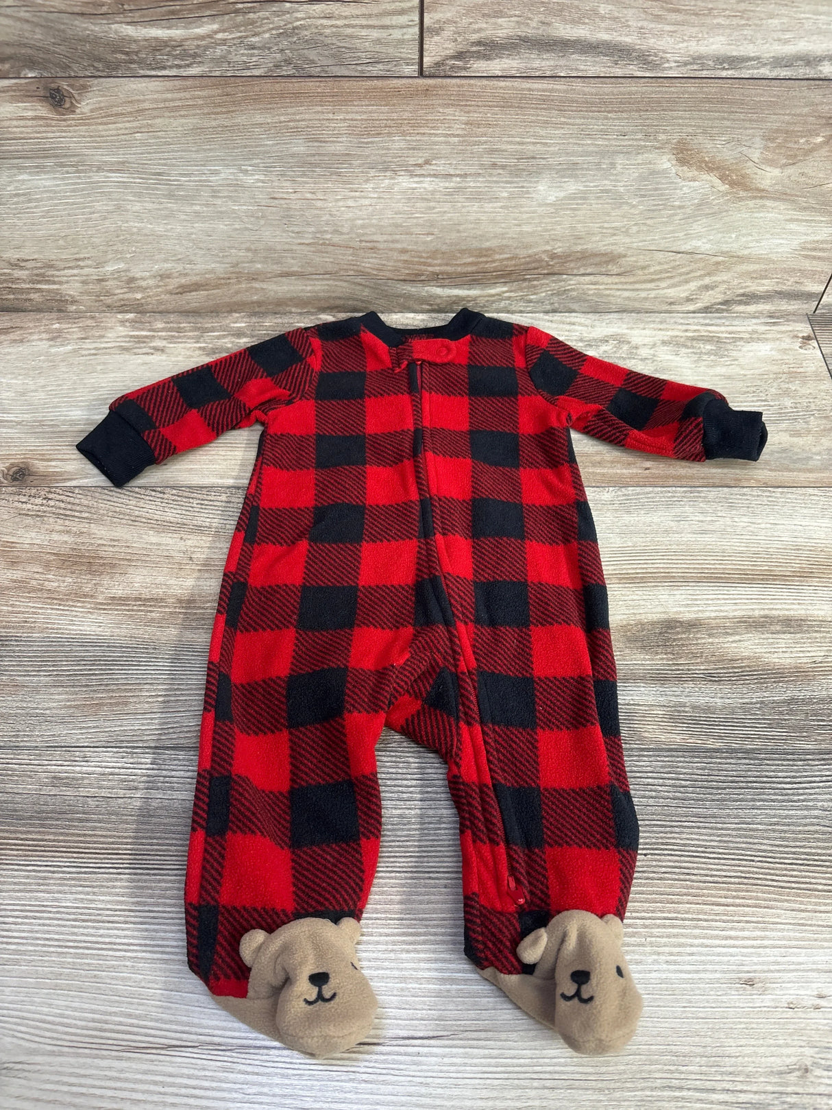 Red and black plaid baby sleeper with bear feet on wood background
