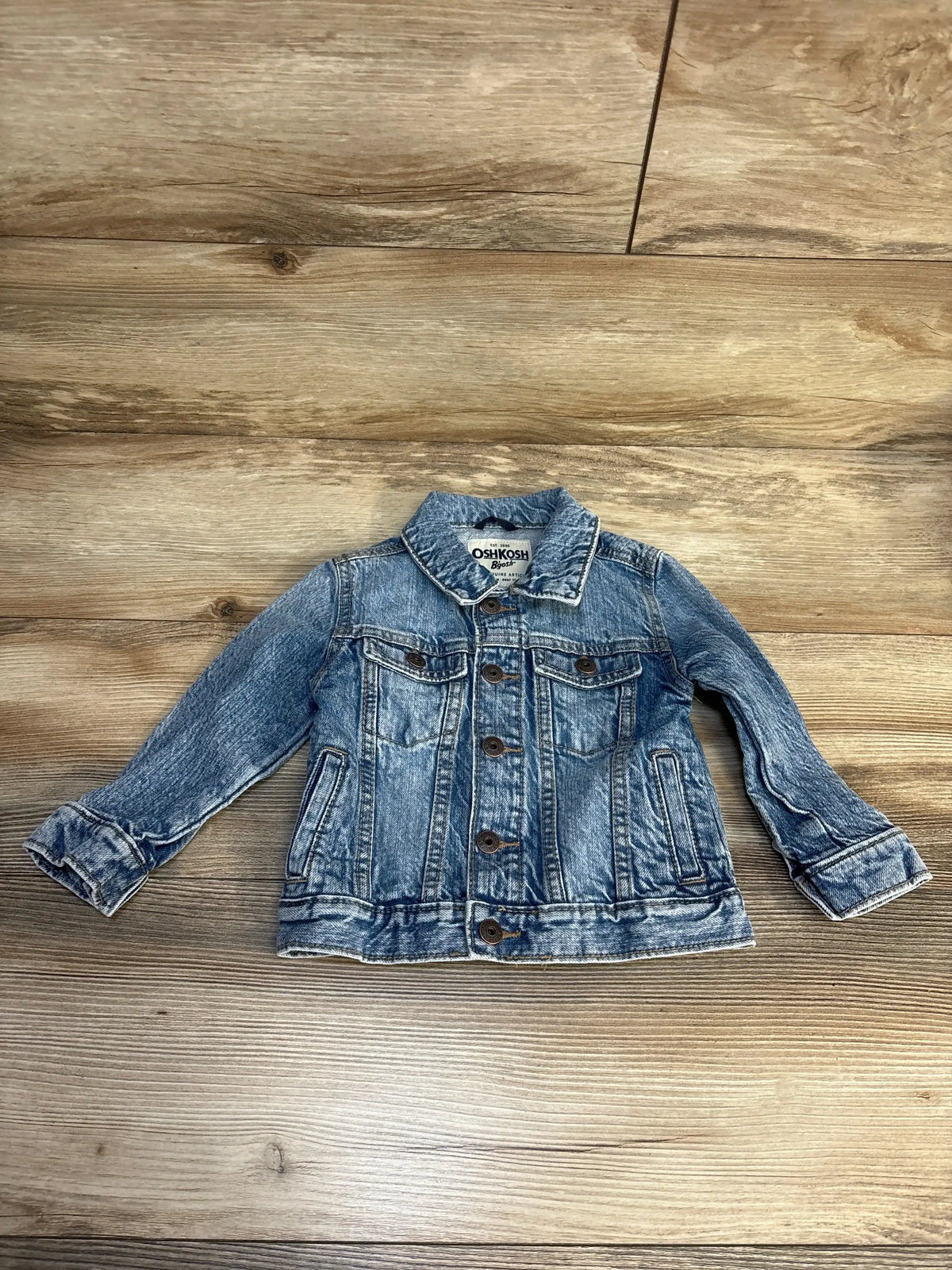 OshKosh kids blue denim jacket with button front on wood background