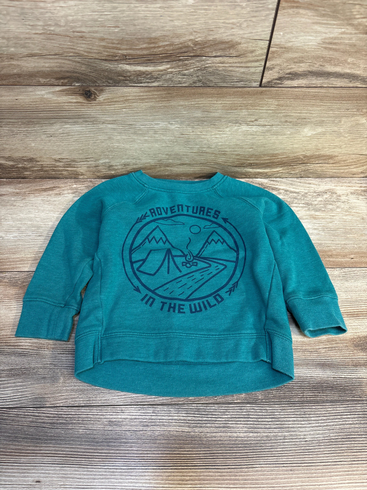 Teal kids pullover with 'Adventures in the Wild' mountain and tent graphic on wood background