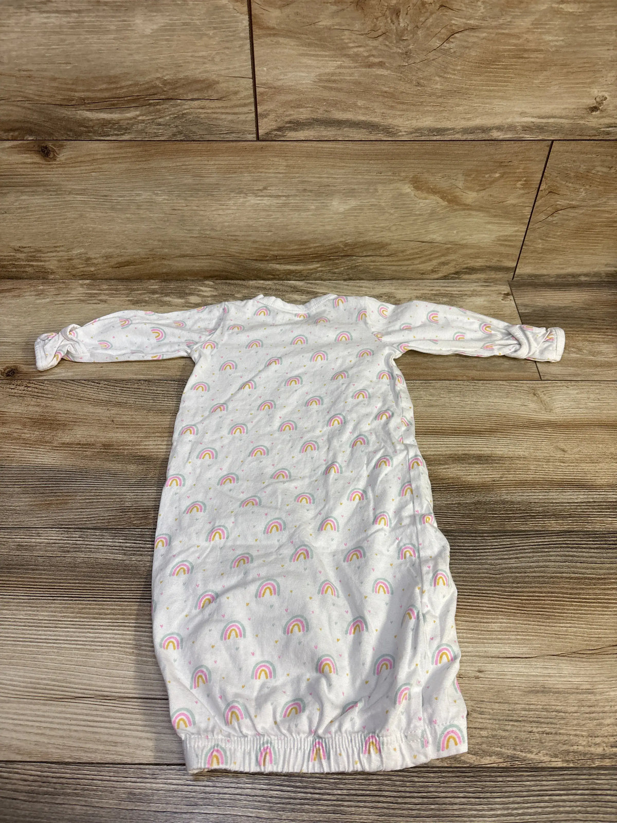 White Cambria baby kimono sleep gown with rainbow print on a wood background