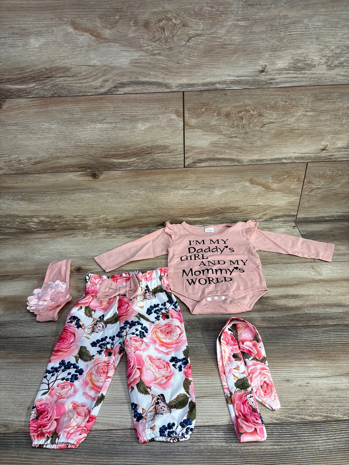 Baby girl outfit with pink floral pants, matching headband, and pink onesie with text