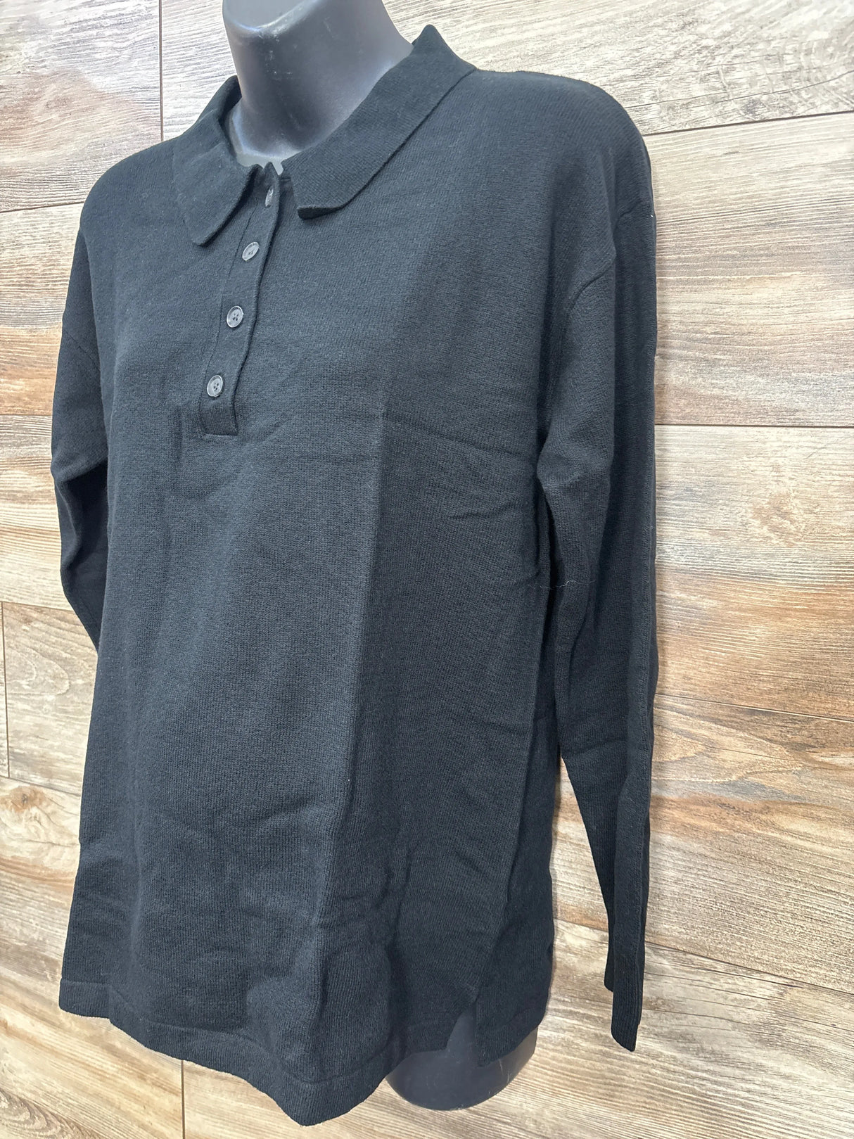 Black long-sleeve knit polo shirt displayed on mannequin against wood panel background