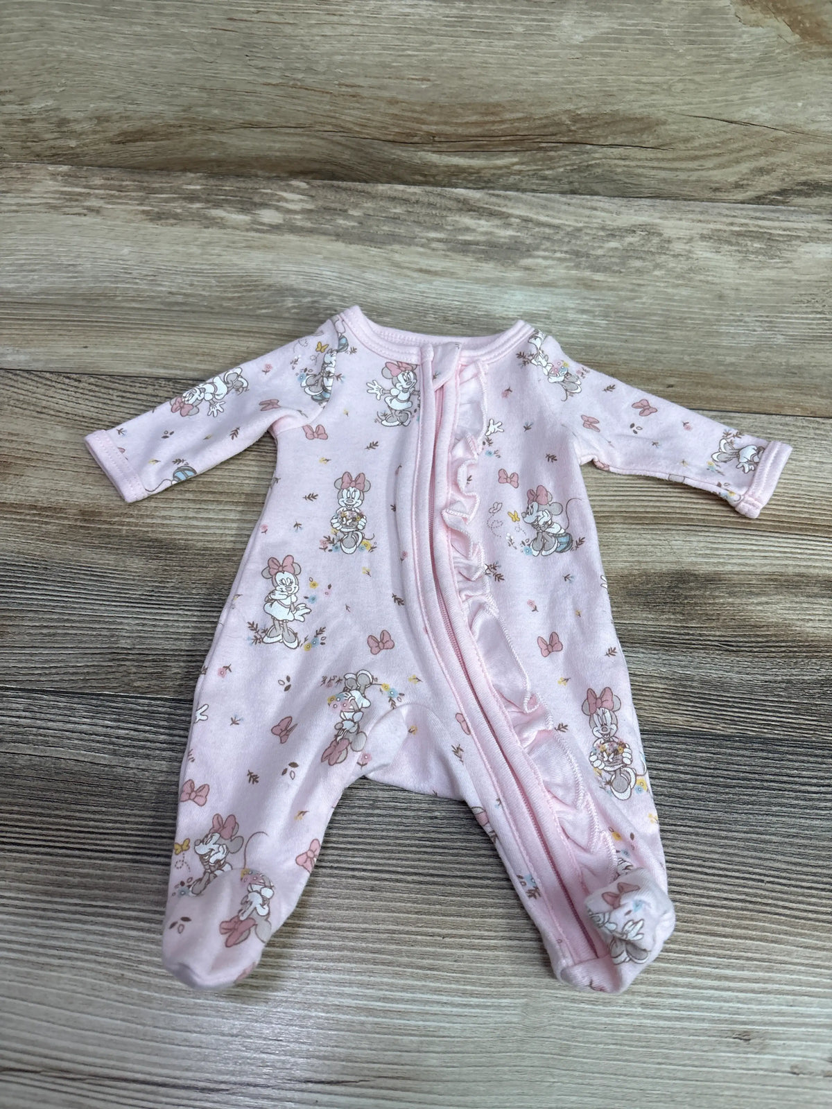 Pink Disney Baby Minnie Mouse preemie sleeper with zipper and bow prints on wood background