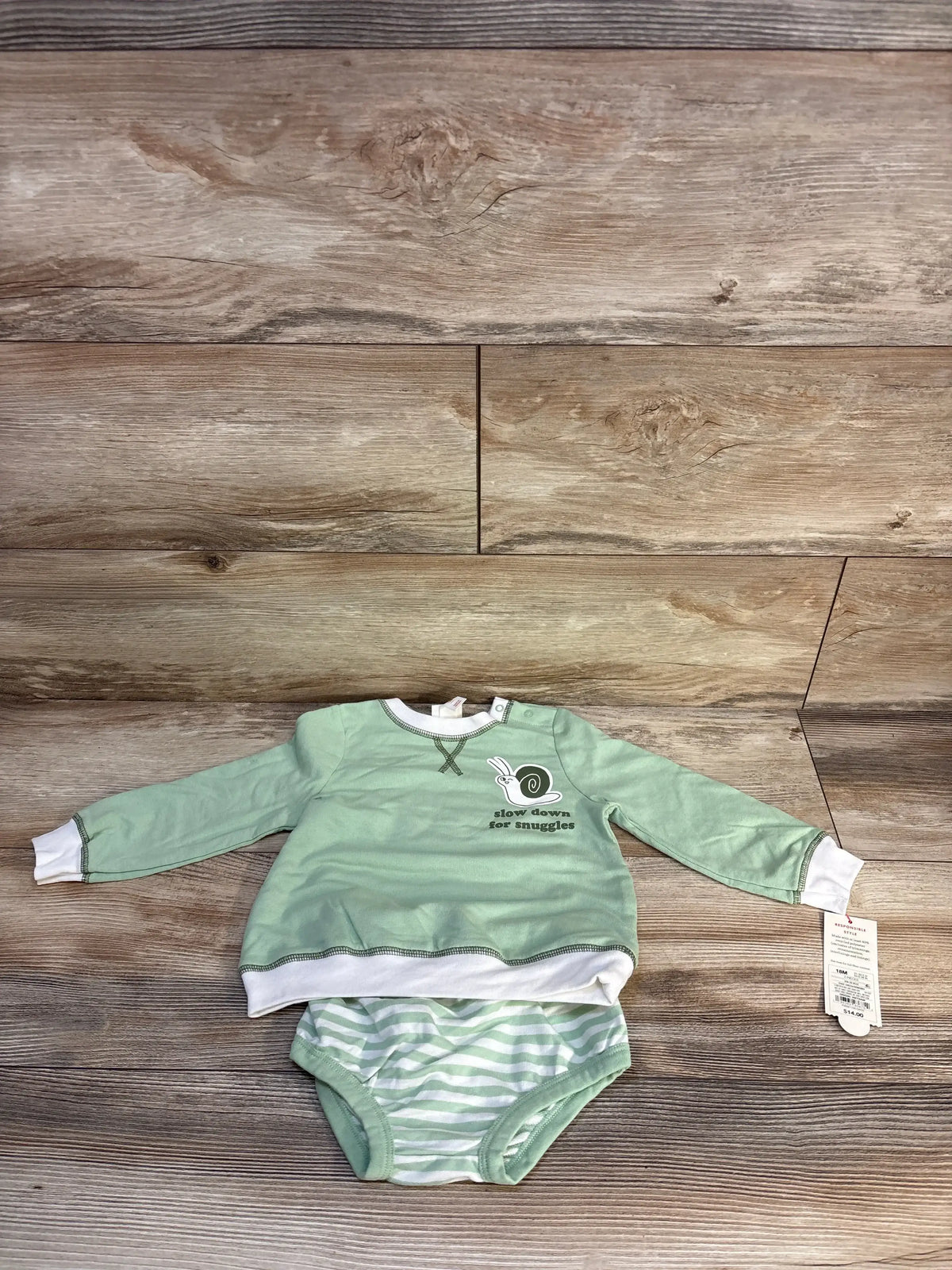 Mint green baby outfit with long sleeve top and striped bodysuit, snail graphic, wood background