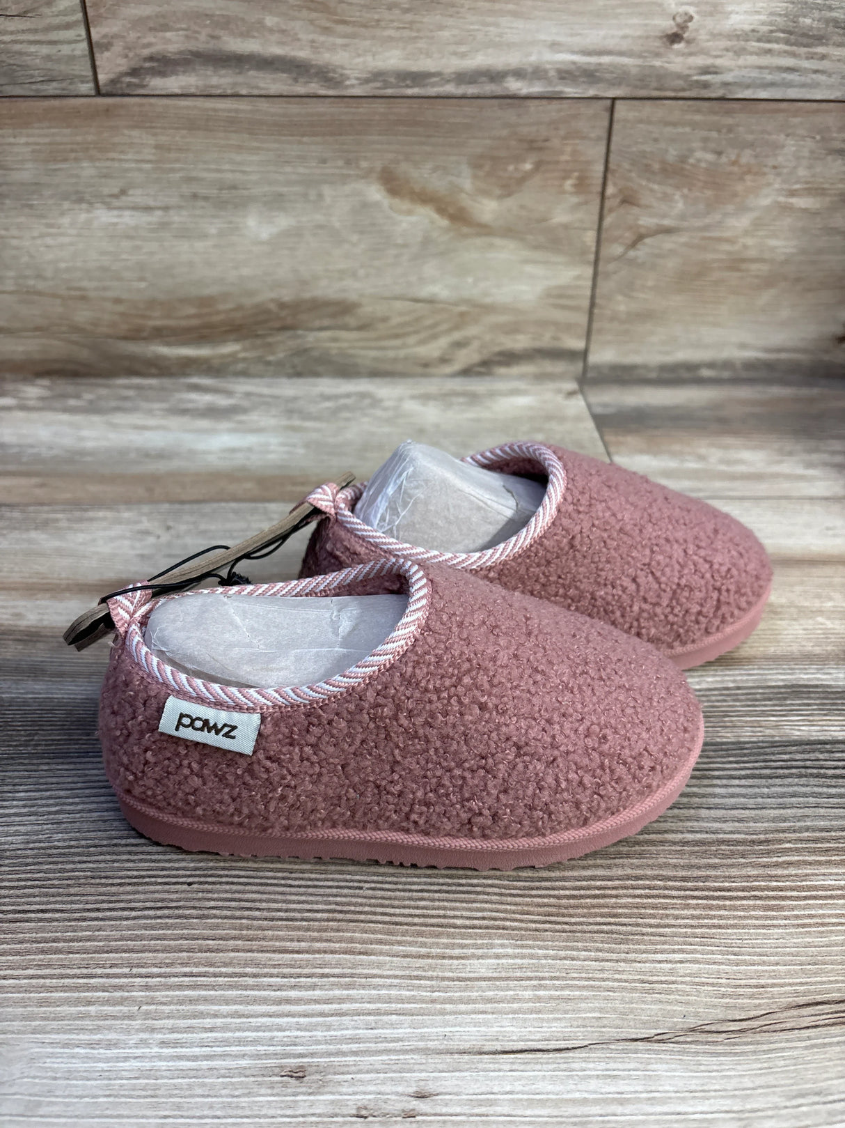 Side view of pink Pawz toddler slippers (size 11/12C) showing sherpa-like upper and rubber sole on wood background