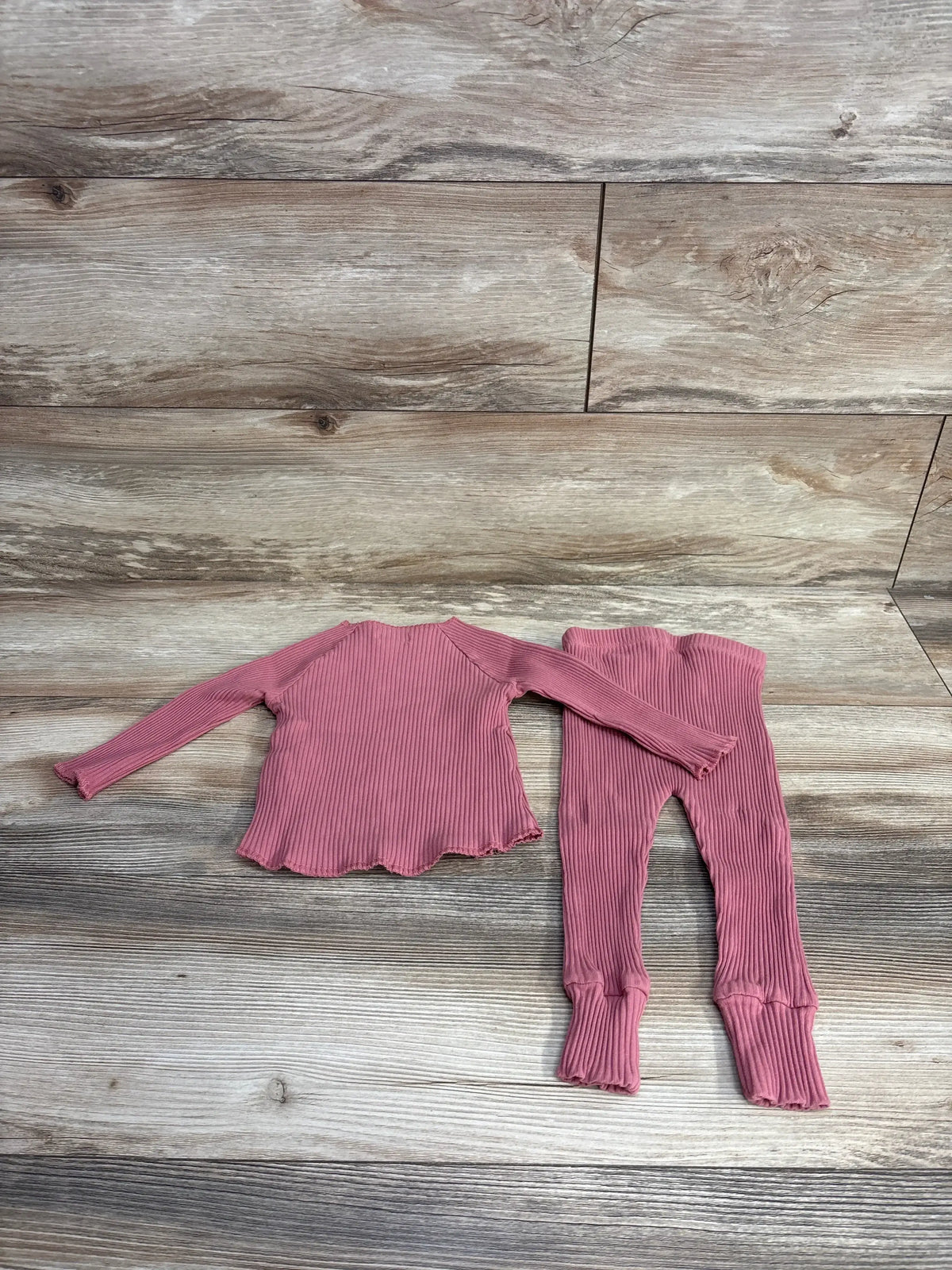 Pink ribbed long sleeve top and matching leggings set for toddlers on wood background