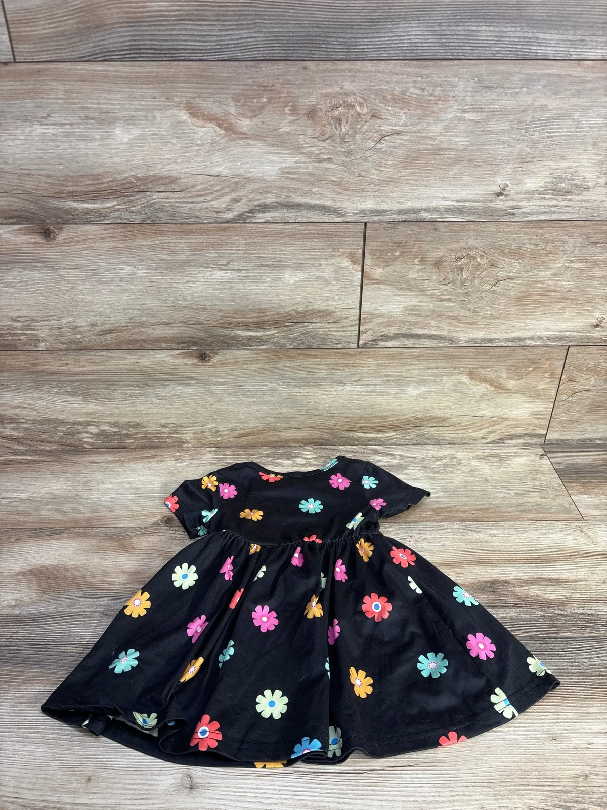 Back view of Shein short sleeve dress in black with colorful daisy floral print and twirl skirt on wood plank floor