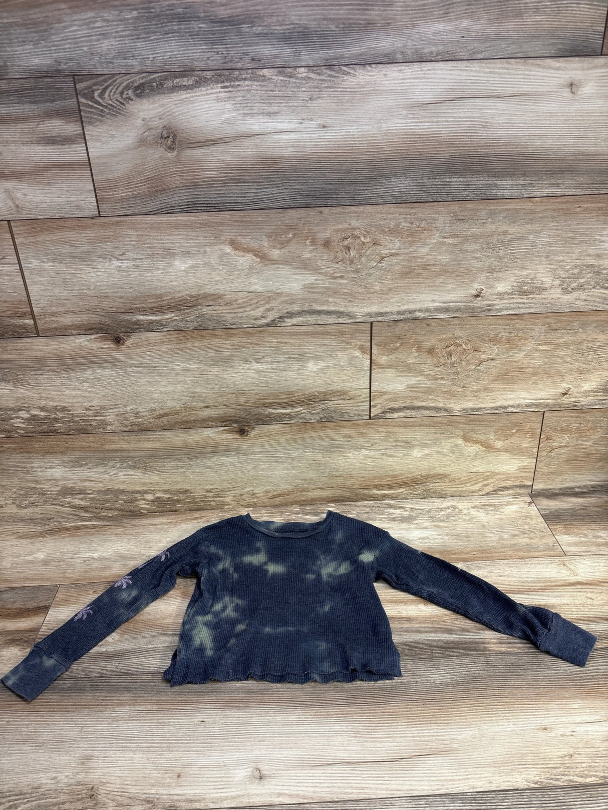 Black and tan tie-dye long sleeve ribbed cropped thermal shirt on wood floor