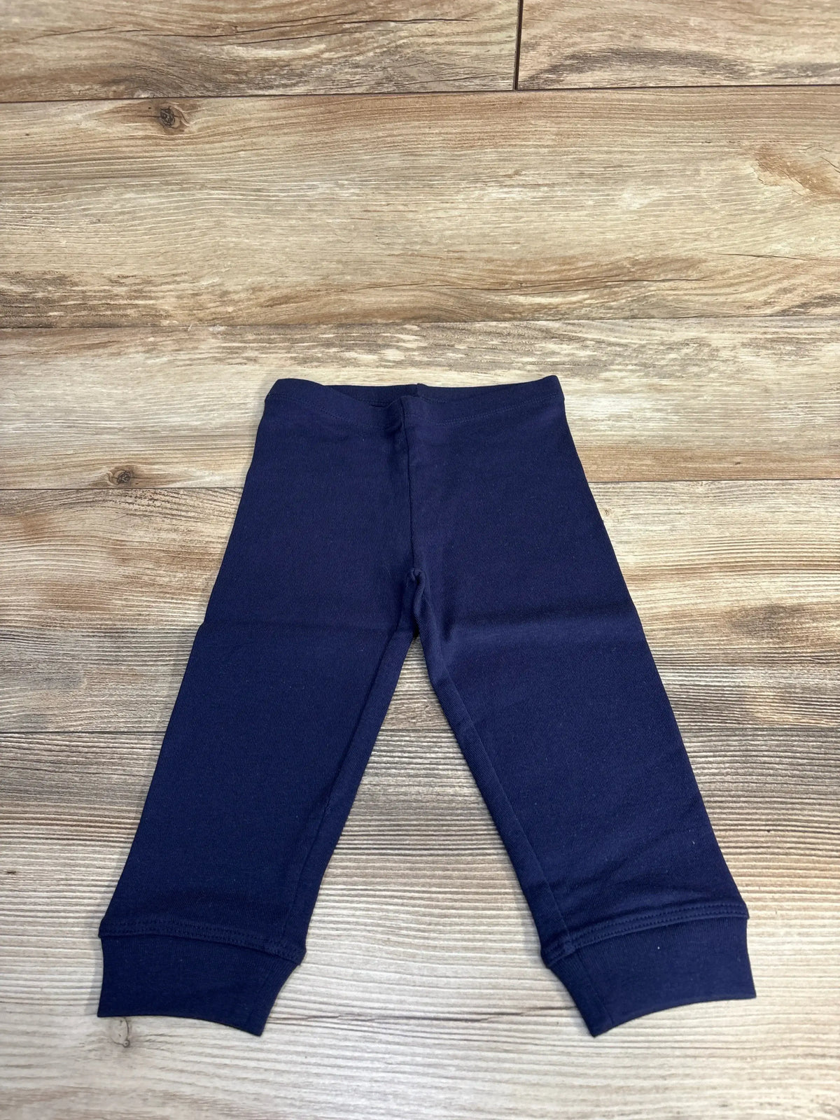 Navy blue baby leggings on wooden floor, soft cotton pants for infants