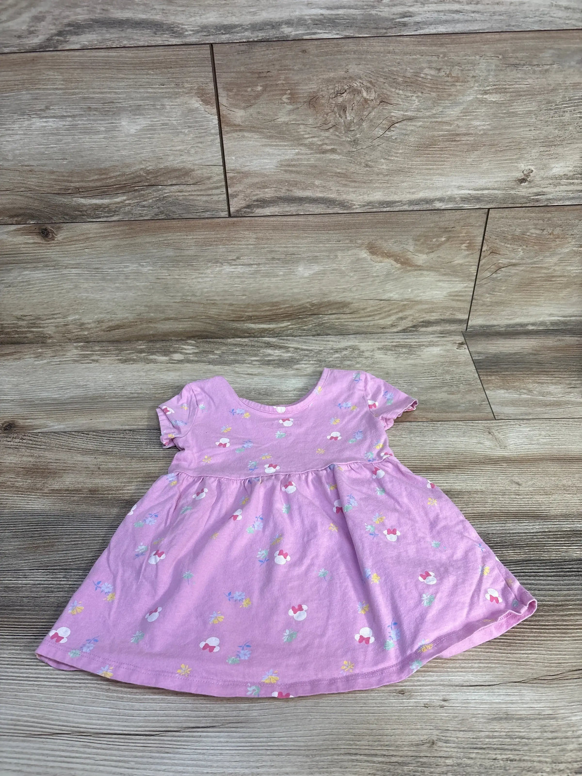 Front view of Baby Gap x Disney Minnie Mouse dress in pink with allover print and short sleeves on wood floor