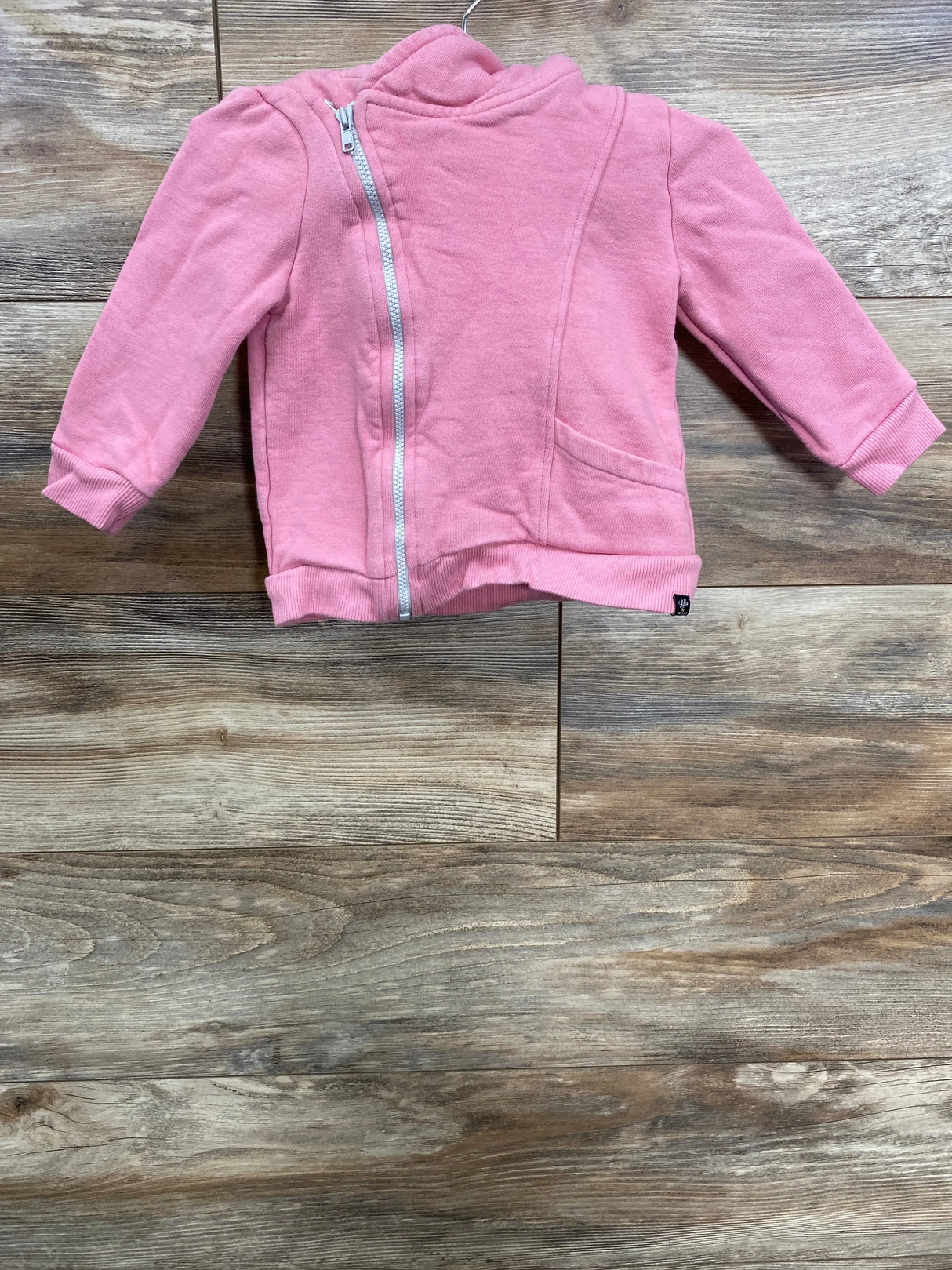 Pink toddler jacket with front zipper and pockets displayed on wooden floor
