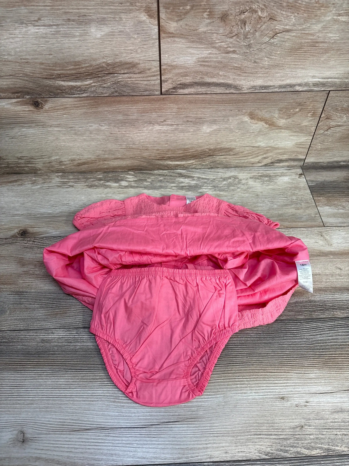 Top-down flat lay of Just One You 2-piece pink dress with matching elastic-waist bloomers, size 18 months, on wood floor