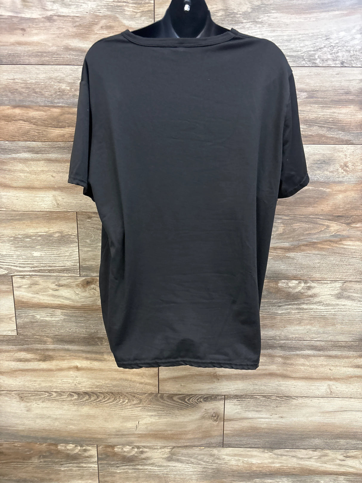 Back view of maternity See You Soon T-shirt in black, oversized with short sleeves on mannequin against wood background