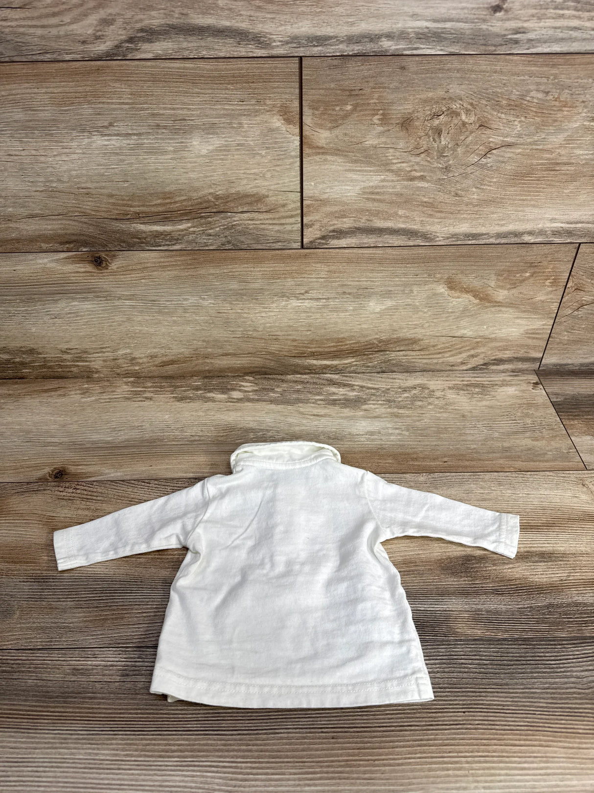 Long sleeve white toddler shirt with turtleneck on wood background, gently used kids clothing
