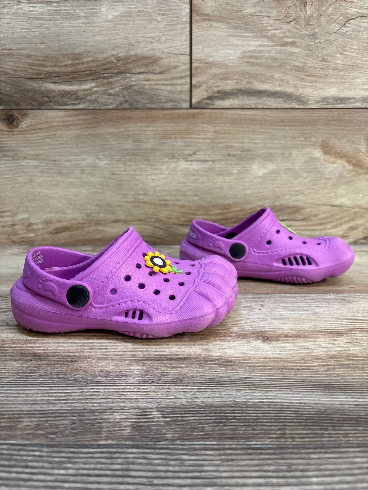 Purple toddler clogs with sunflower charm on wood background, kids footwear resale