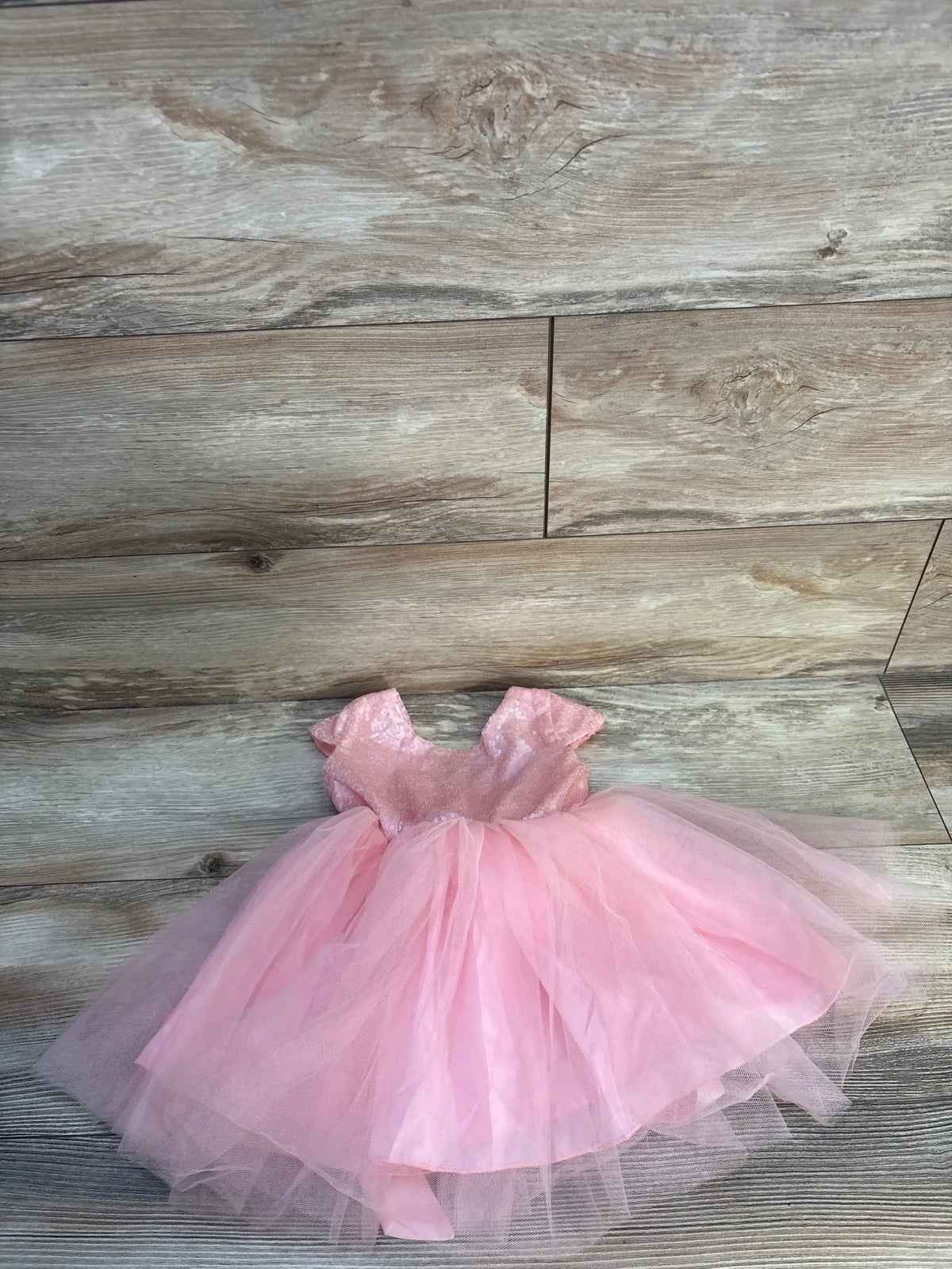 Pink toddler tutu dress with sequined bodice and tulle skirt on wooden floor