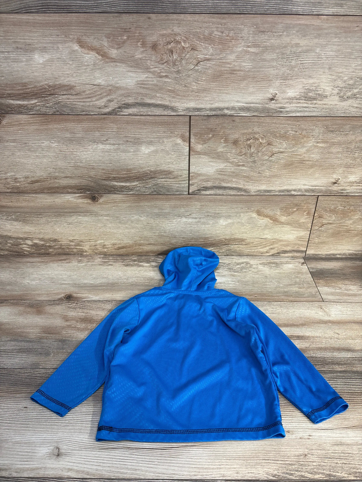Back view of Body Glove blue hooded quarter-zip rash guard shirt showcasing long sleeves and hood on a wood-grain background