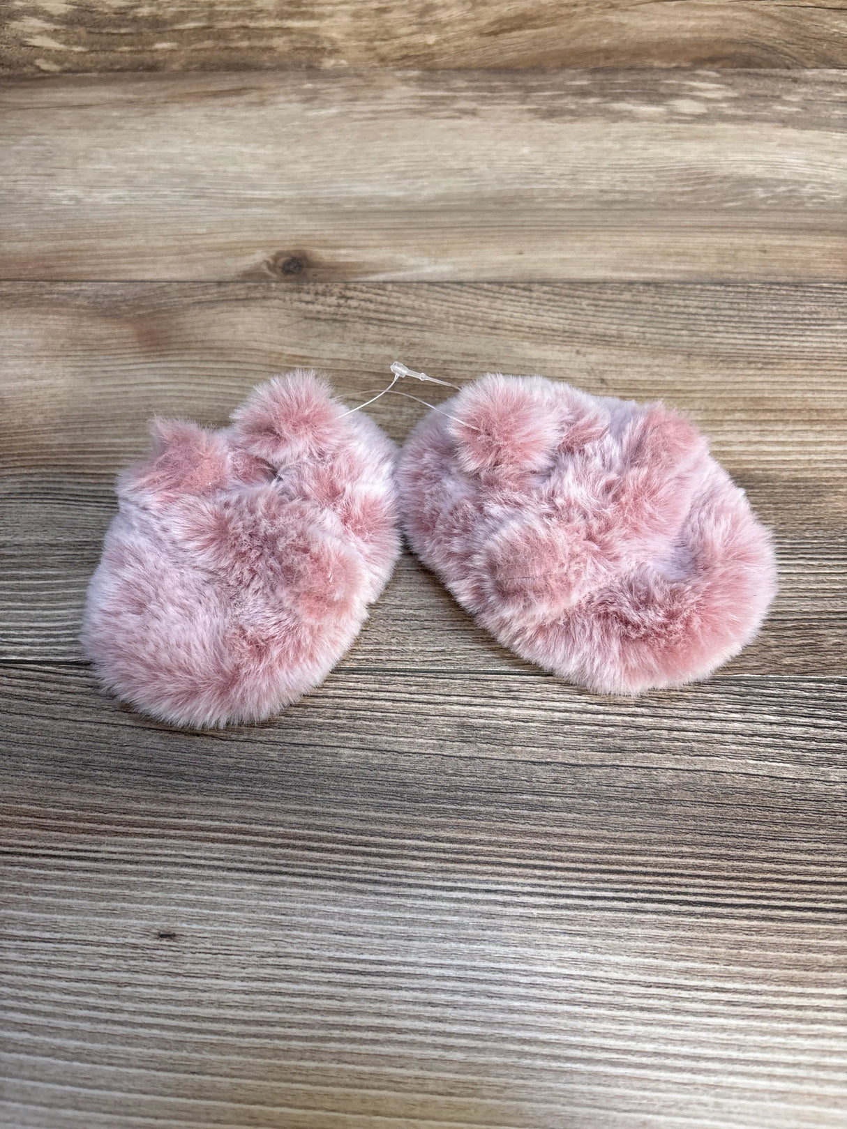 Pink faux fur baby booties on wood background, cozy kids footwear