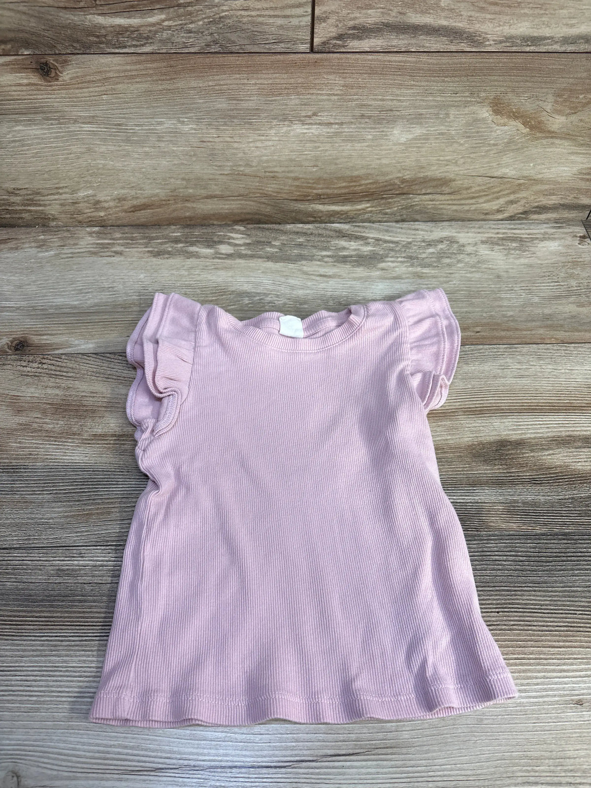 Flat lay of Baby Gap ribbed pink toddler shirt size 4T showcasing flutter sleeves and crew neck on wood background