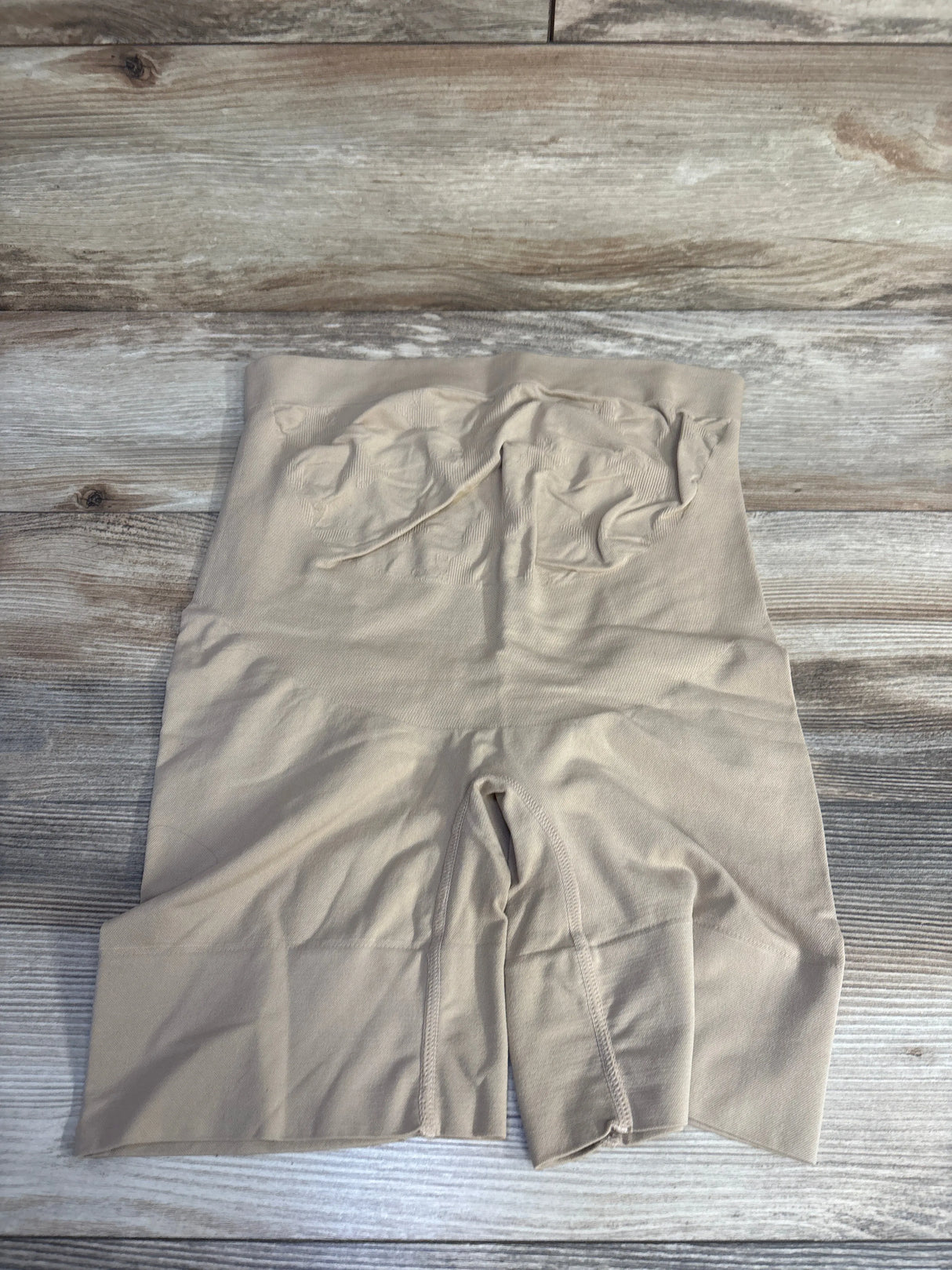 Beige high-waisted shapewear shorts on wood floor, seamless slimming underwear