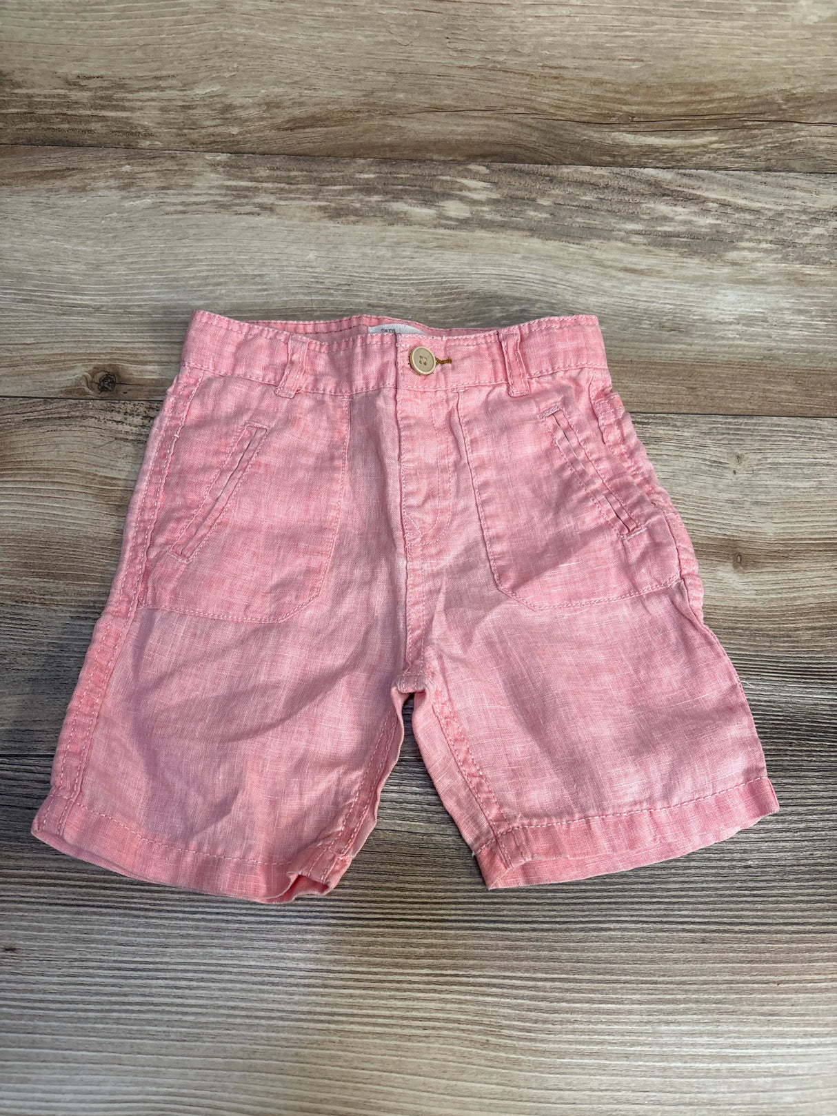 Pink toddler shorts with front pockets on wood background, gently used kids clothing.