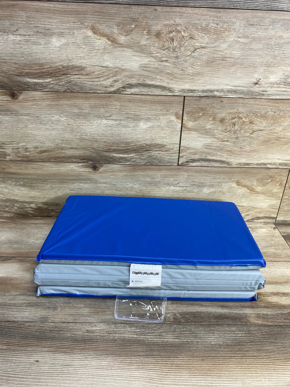 Folded view of ProSource Four-Fold Kids Rest Nap Mat showcasing blue vinyl covering and thick foam padding on a wood floor