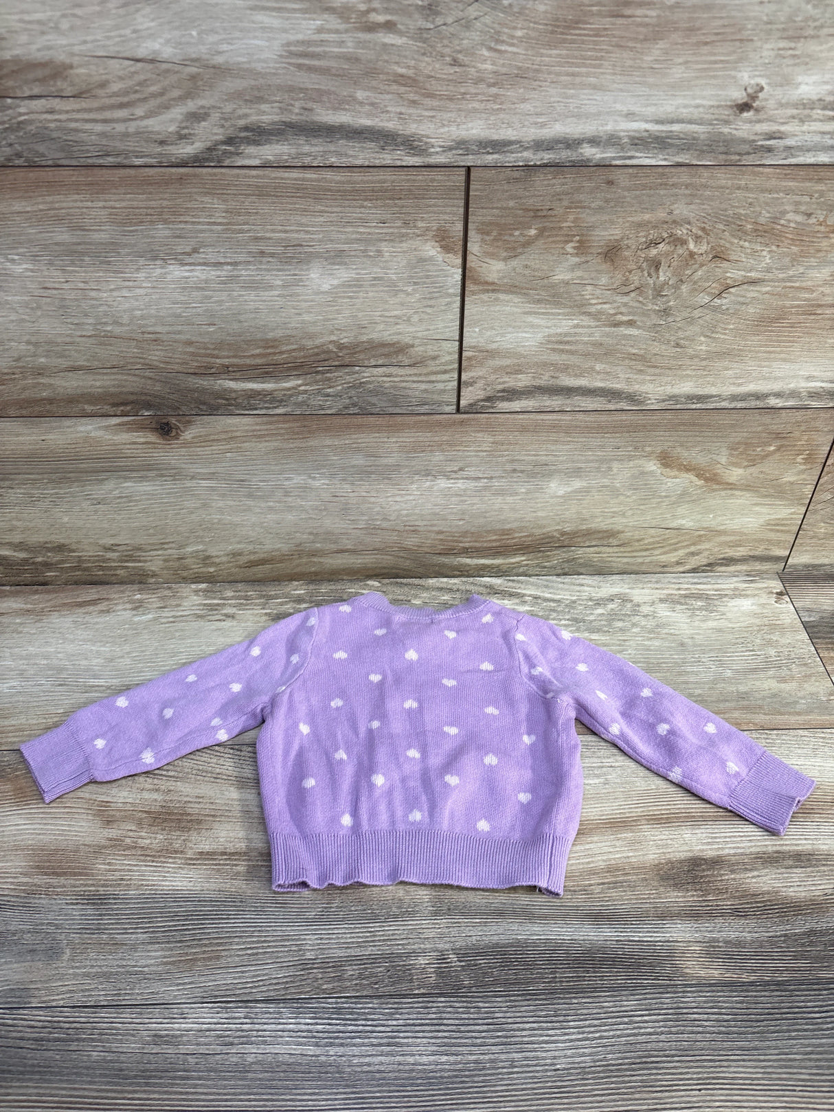 Back view of Cat & Jack heart-print knit button-up cardigan (12 months) showcasing white heart pattern and ribbed hem on wood floor
