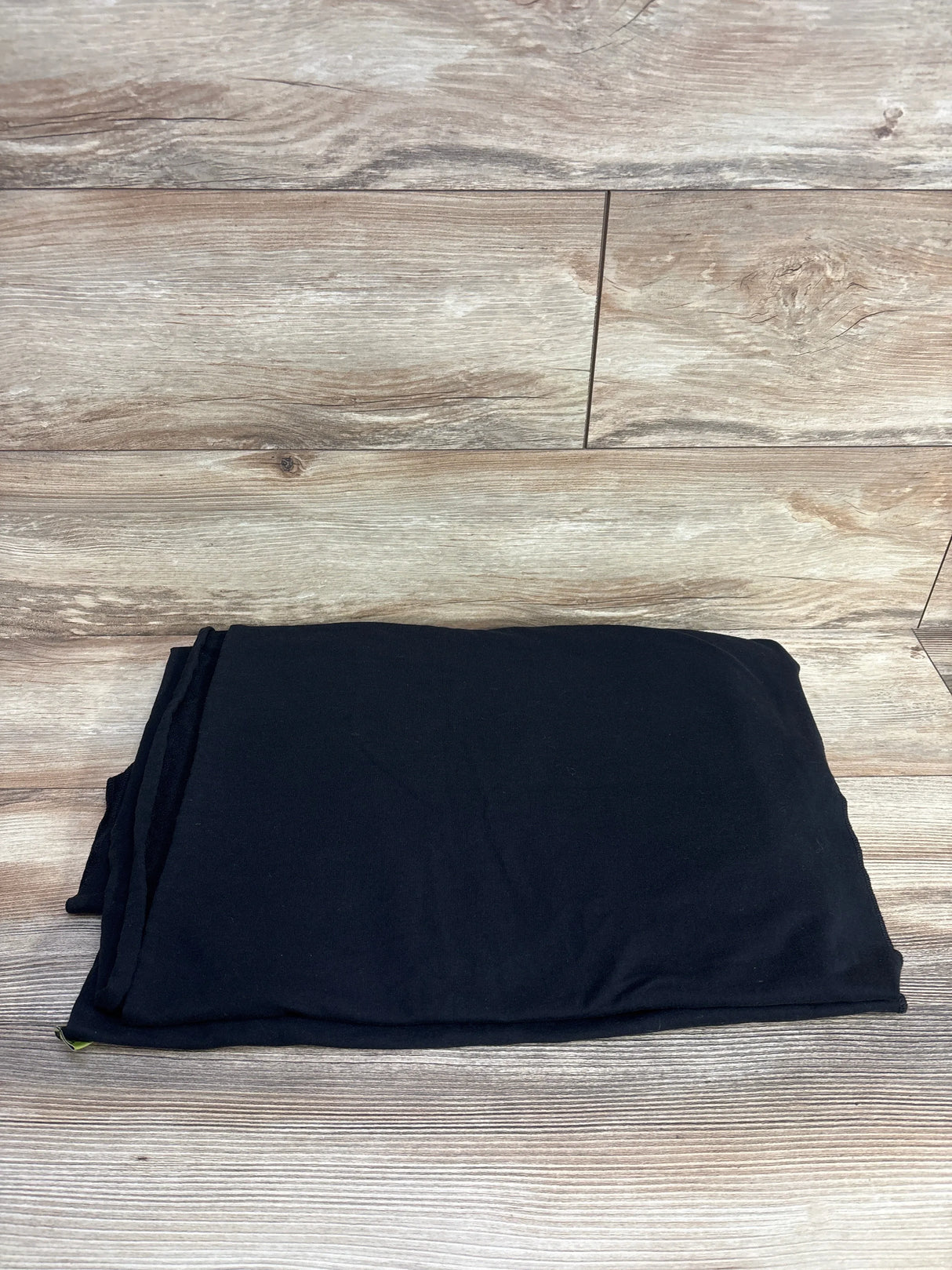 Folded Boba Classic baby wrap in black showing soft fabric and compact fold on wood background