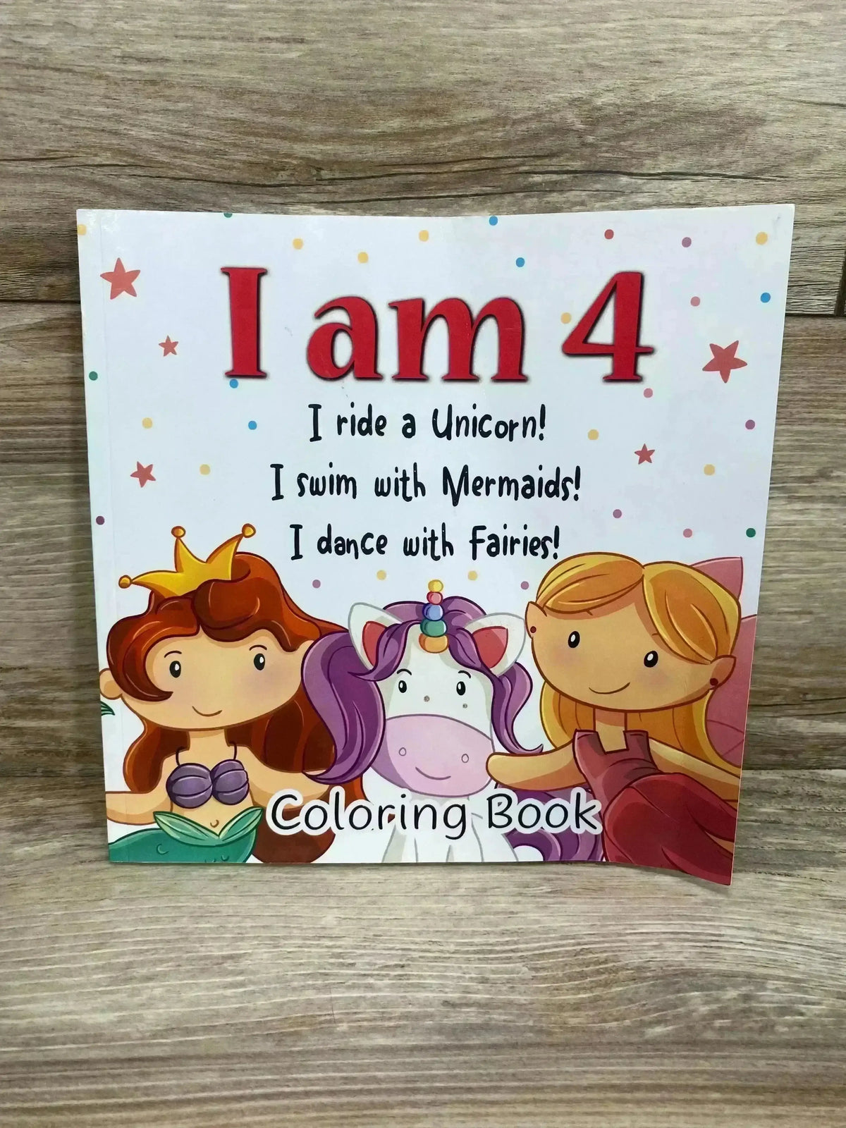 Front view of I Am 4 coloring book cover showcasing large red title and mermaid, unicorn, and fairy illustrations on wood background