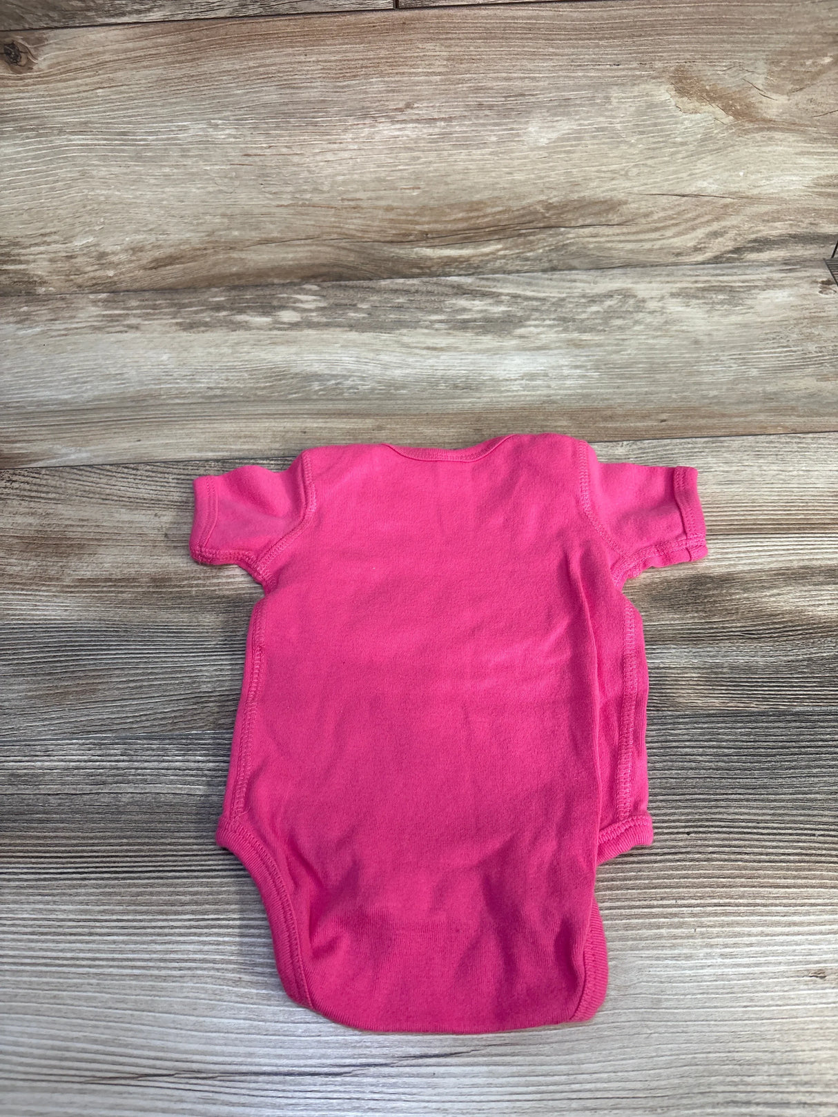 Back view of Rabbit Skins 6m If You Mess With Me bodysuit showcasing solid hot pink short sleeve cotton on wood plank floor