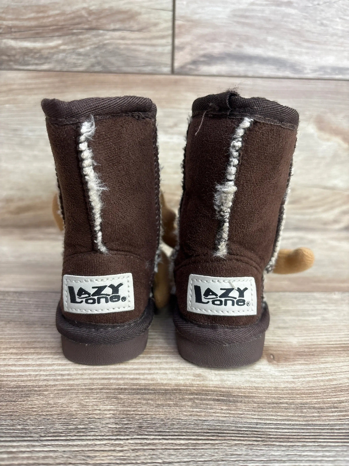 Brown Lazy One toddler booties with faux fur lining on wooden floor