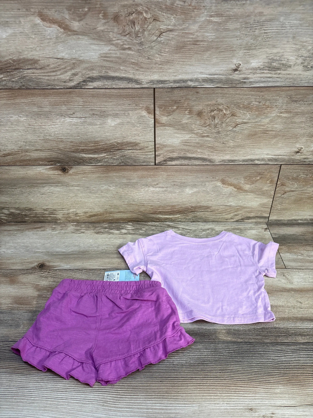 New Cat & Jack 2pc lilac t-shirt and ruffled shorts set for toddlers on a wood background