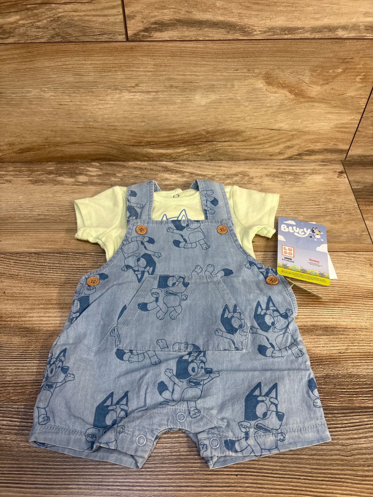 Bluey baby overalls with yellow shirt, denim print, wooden floor