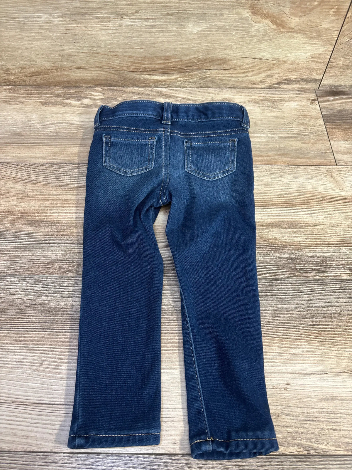 Back view of Cat & Jack toddler blue jeggings size 2T showcasing back pockets, belt loops, and straight legs on wood floor