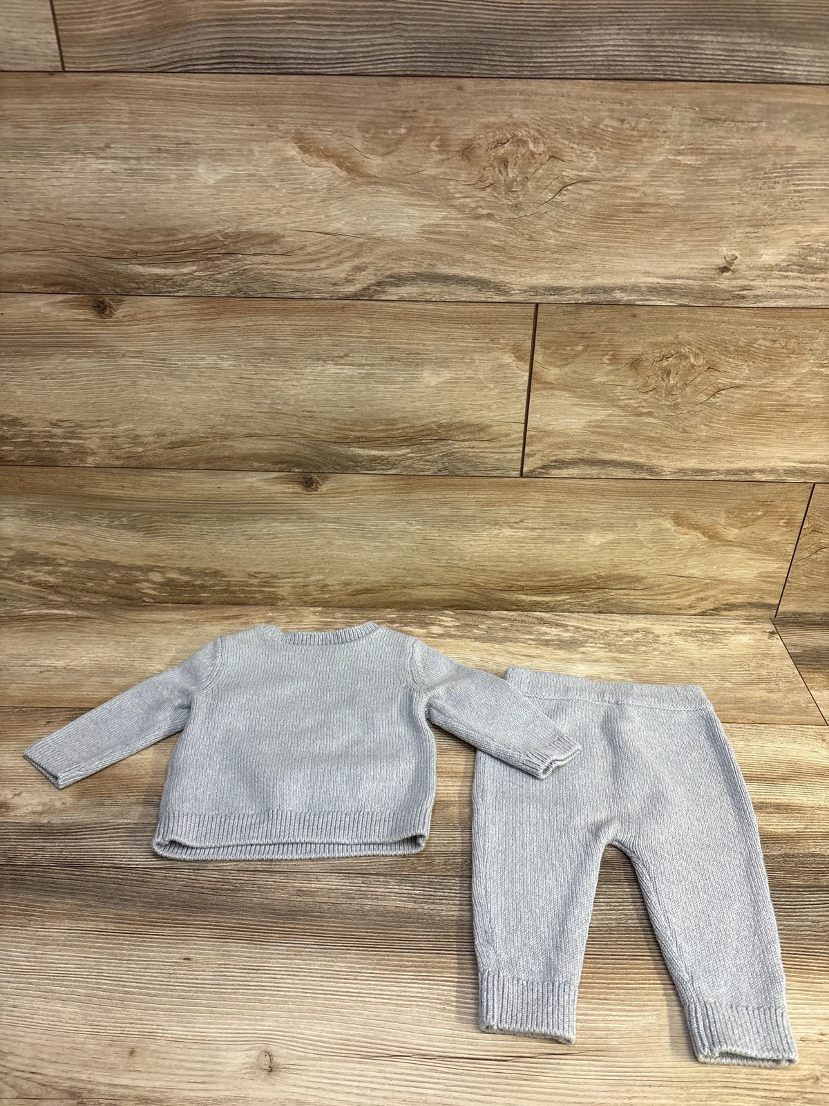 Flat lay of Carter’s grey 2-piece knit sweater and pants (9 months) showing ribbed hems and cuffs with wood background