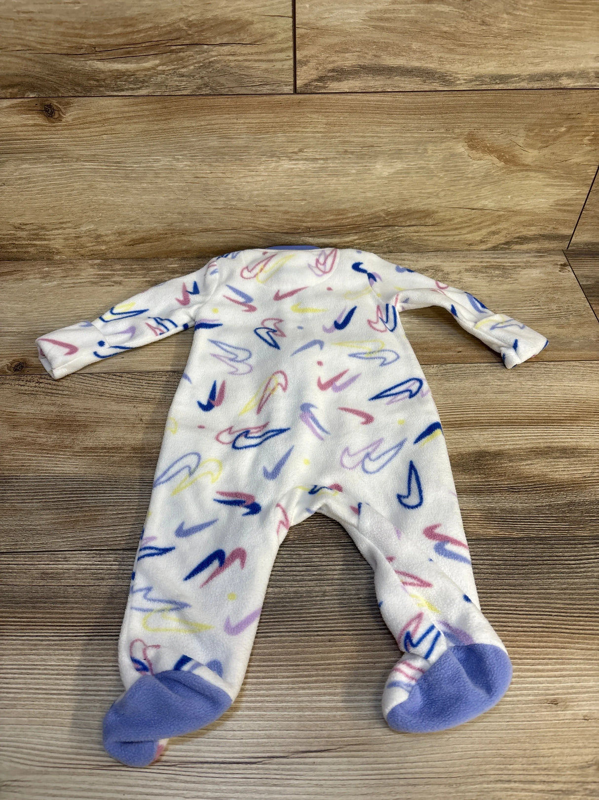 Fleece baby sleeper with colorful abstract print and purple footies on wood floor