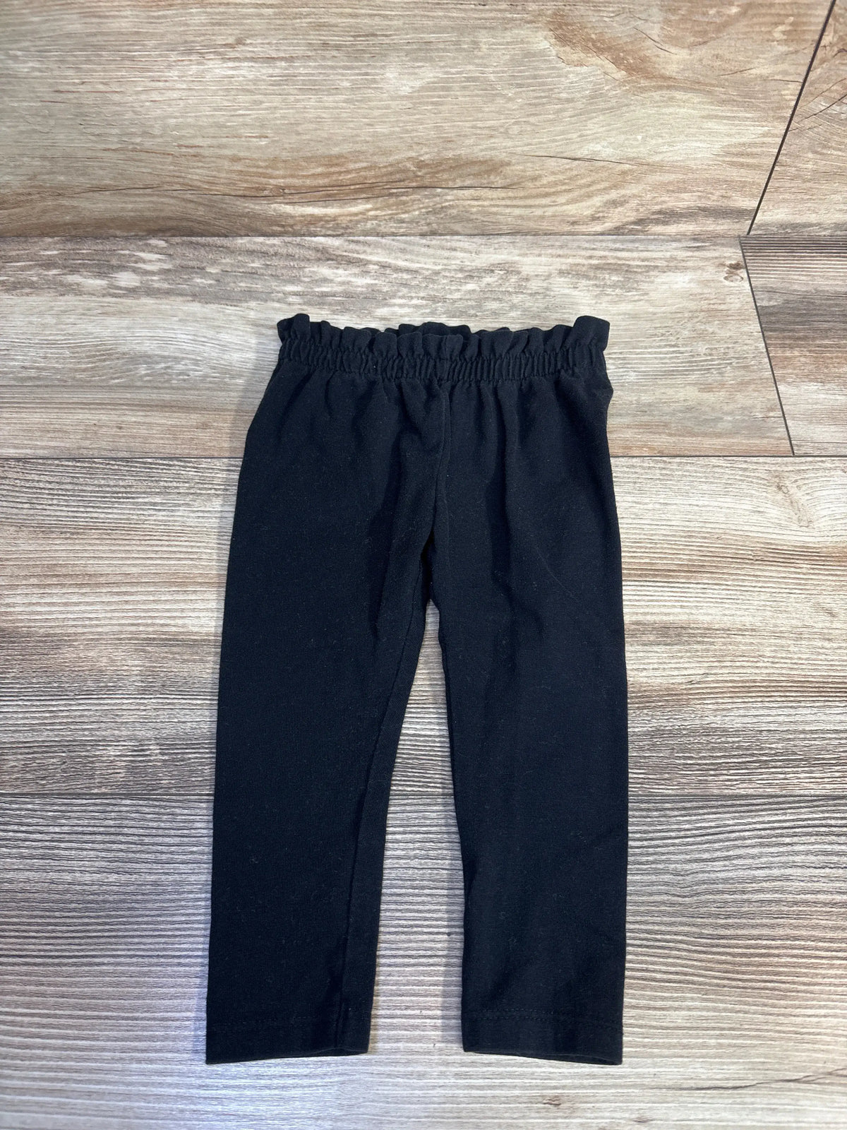 Black Cat & Jack baby leggings size 12m on a wooden surface