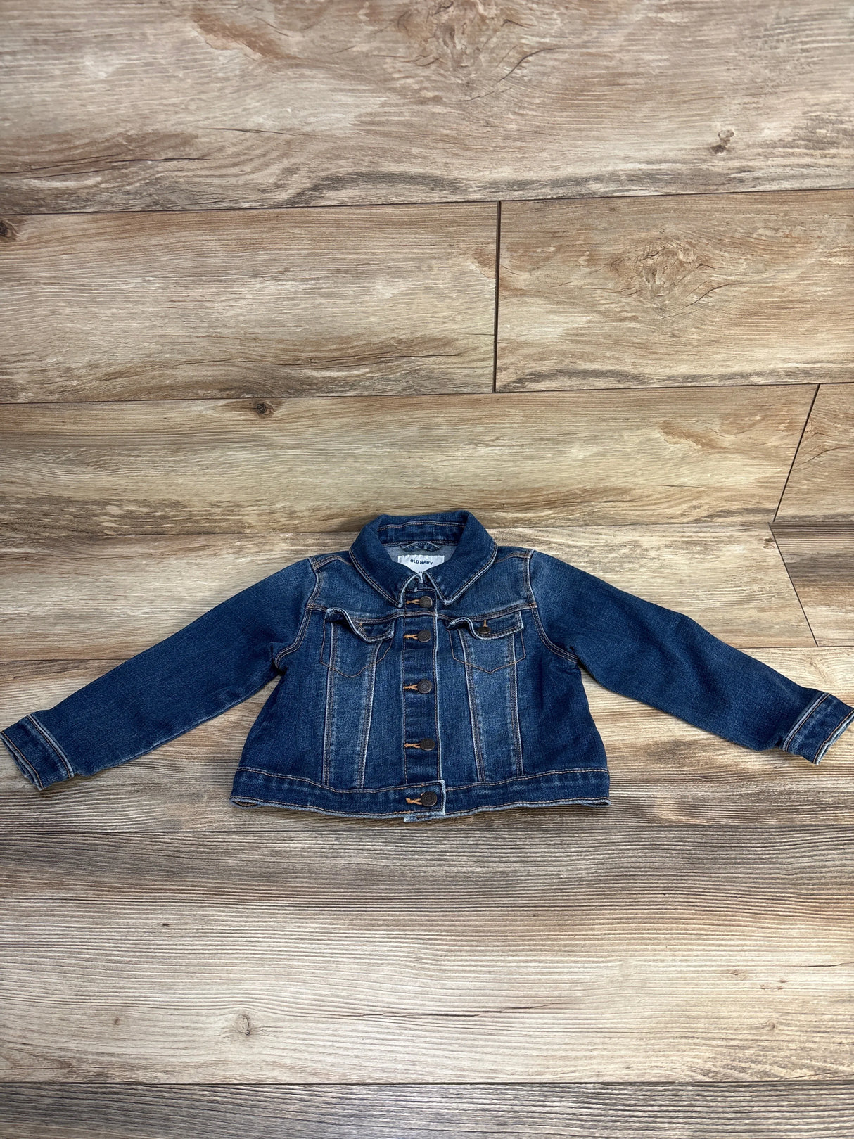Kids denim jacket with long sleeves and button front on wooden background