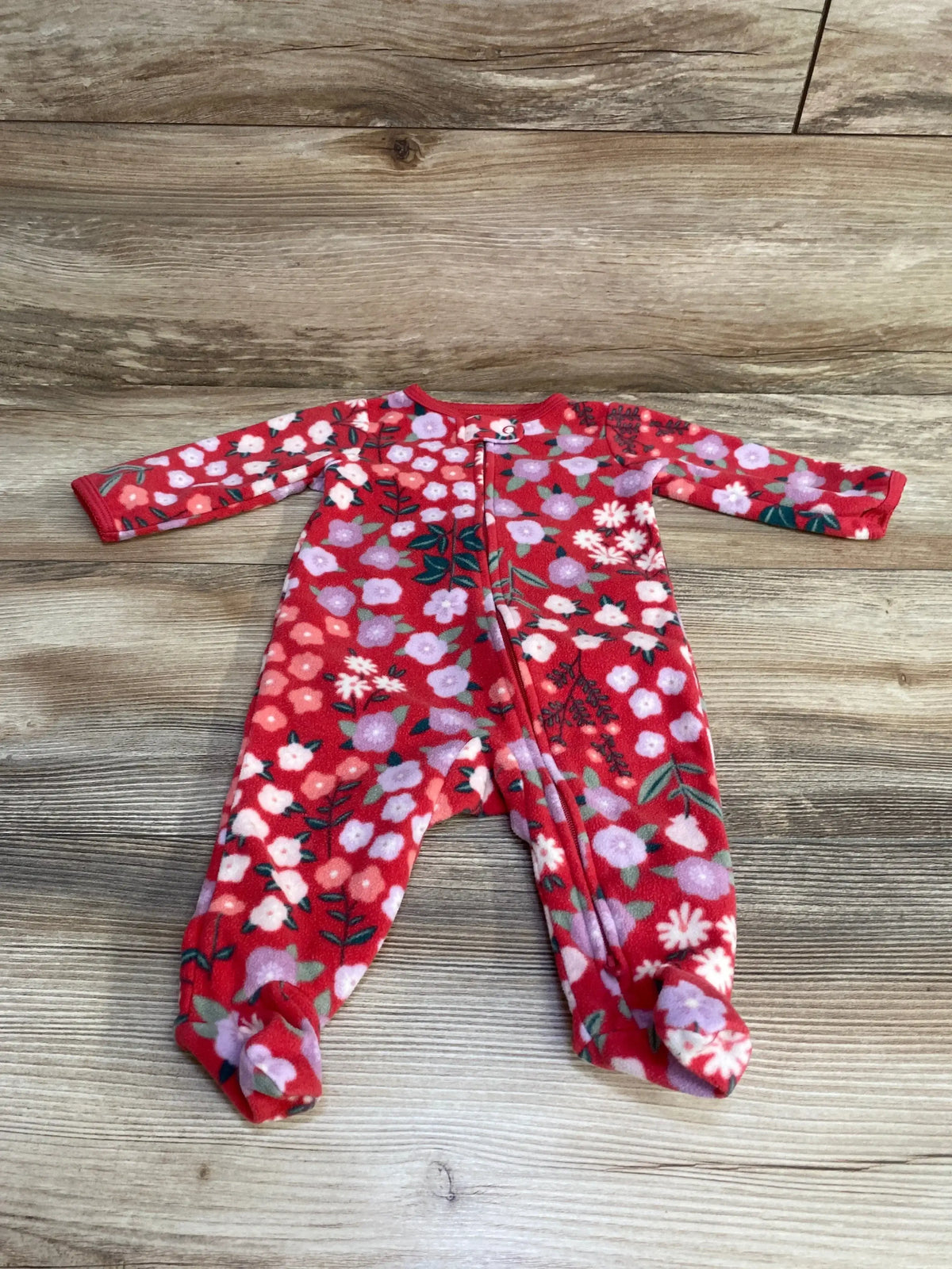 Flat lay of red Carter’s floral footed sleeper 3M with front zipper and all-over flower print on wood background