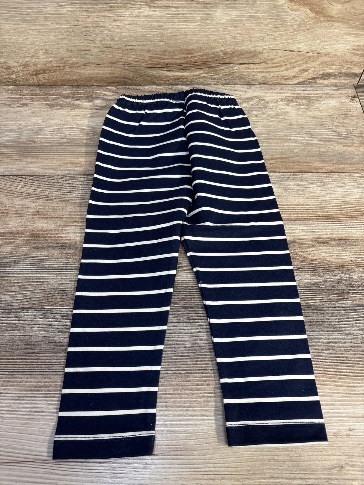 Navy blue and white striped kids leggings on wood background